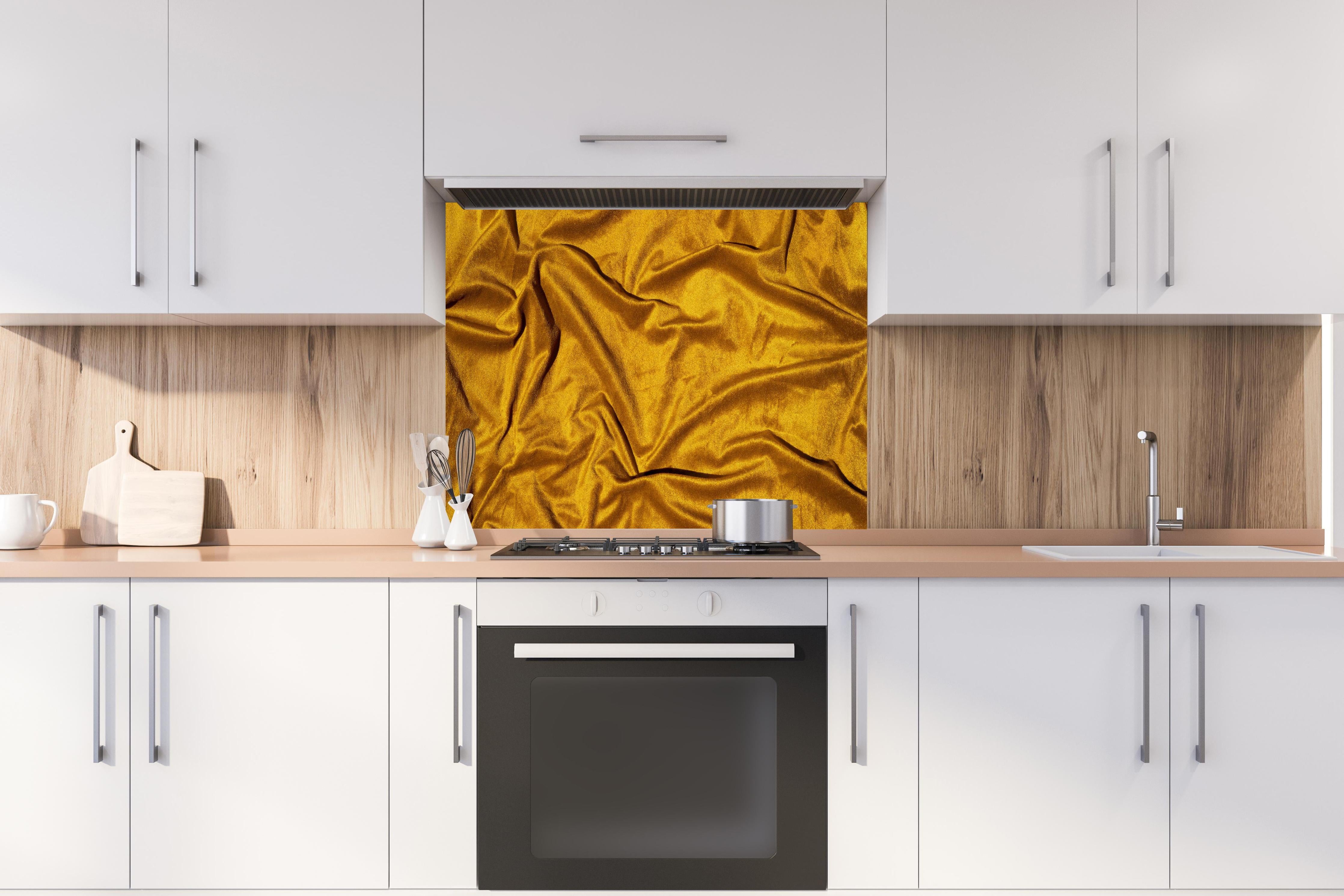 Spritzschutz - Gelbe Satin Seide hinter einem Cerankochfeld zwischen Holz-Kochutensilien
