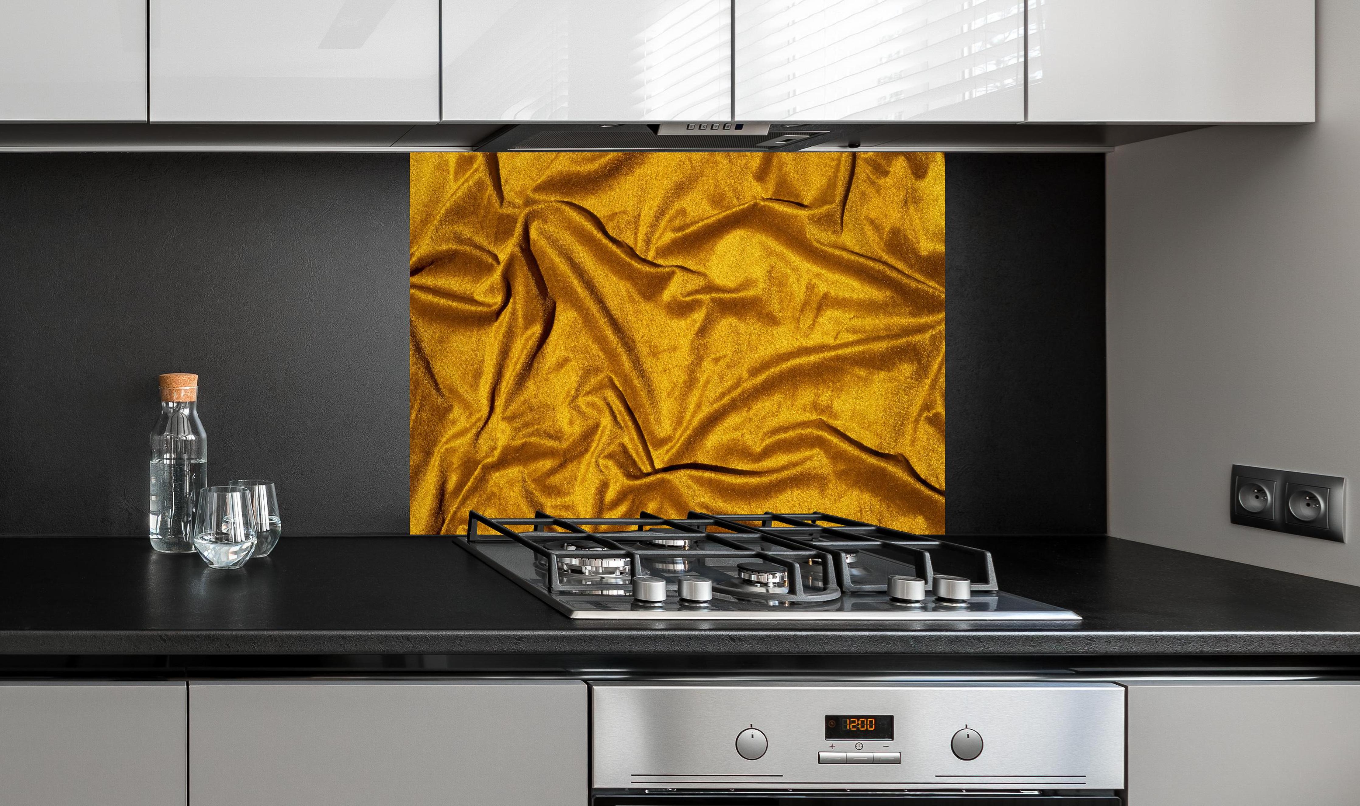 Spritzschutz - Gelbe Satin Seide hinter einem Cerankochfeld zwischen Holz-Kochutensilien
