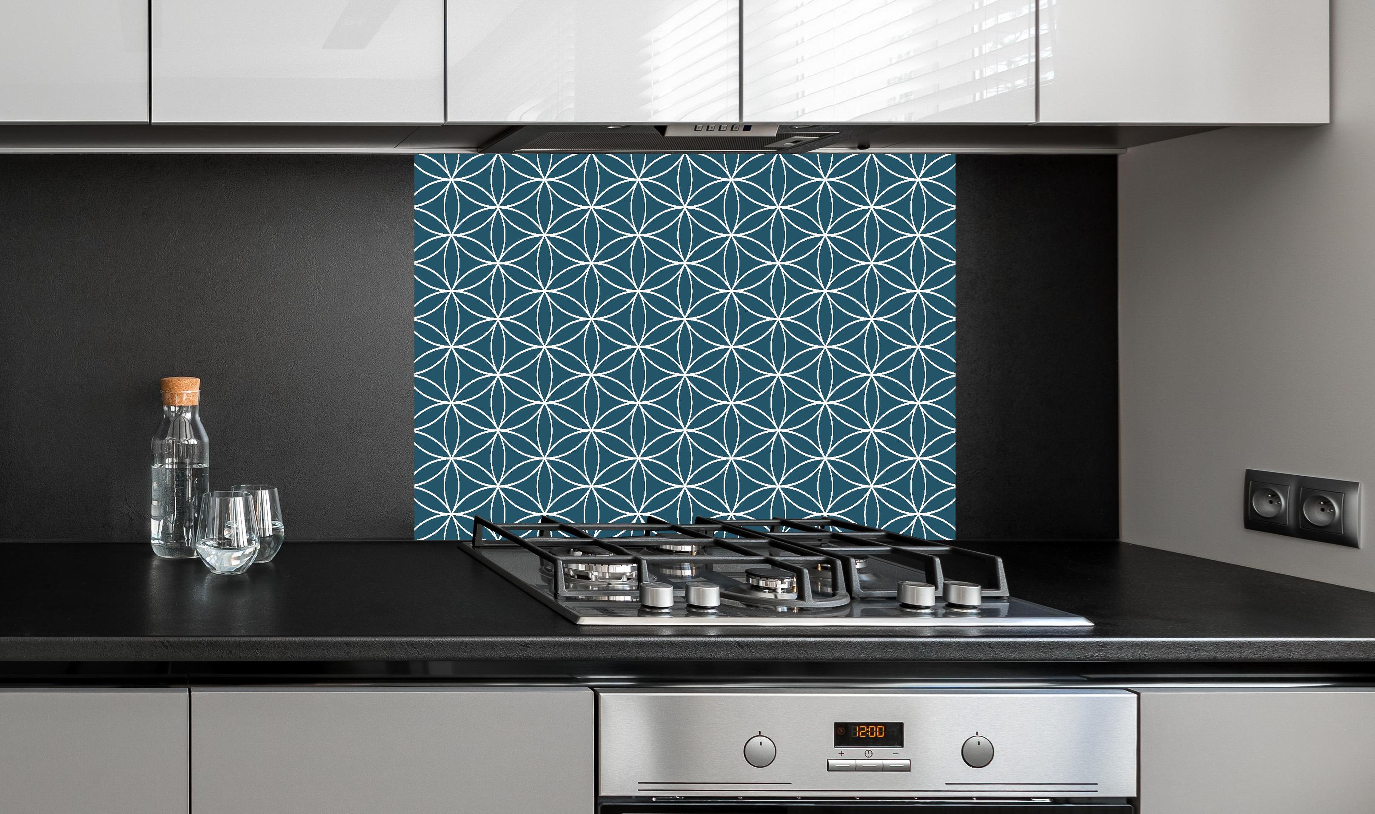 Spritzschutz - Geometrica Fiori Blu Petrolio hinter einem Cerankochfeld zwischen Holz-Kochutensilien
