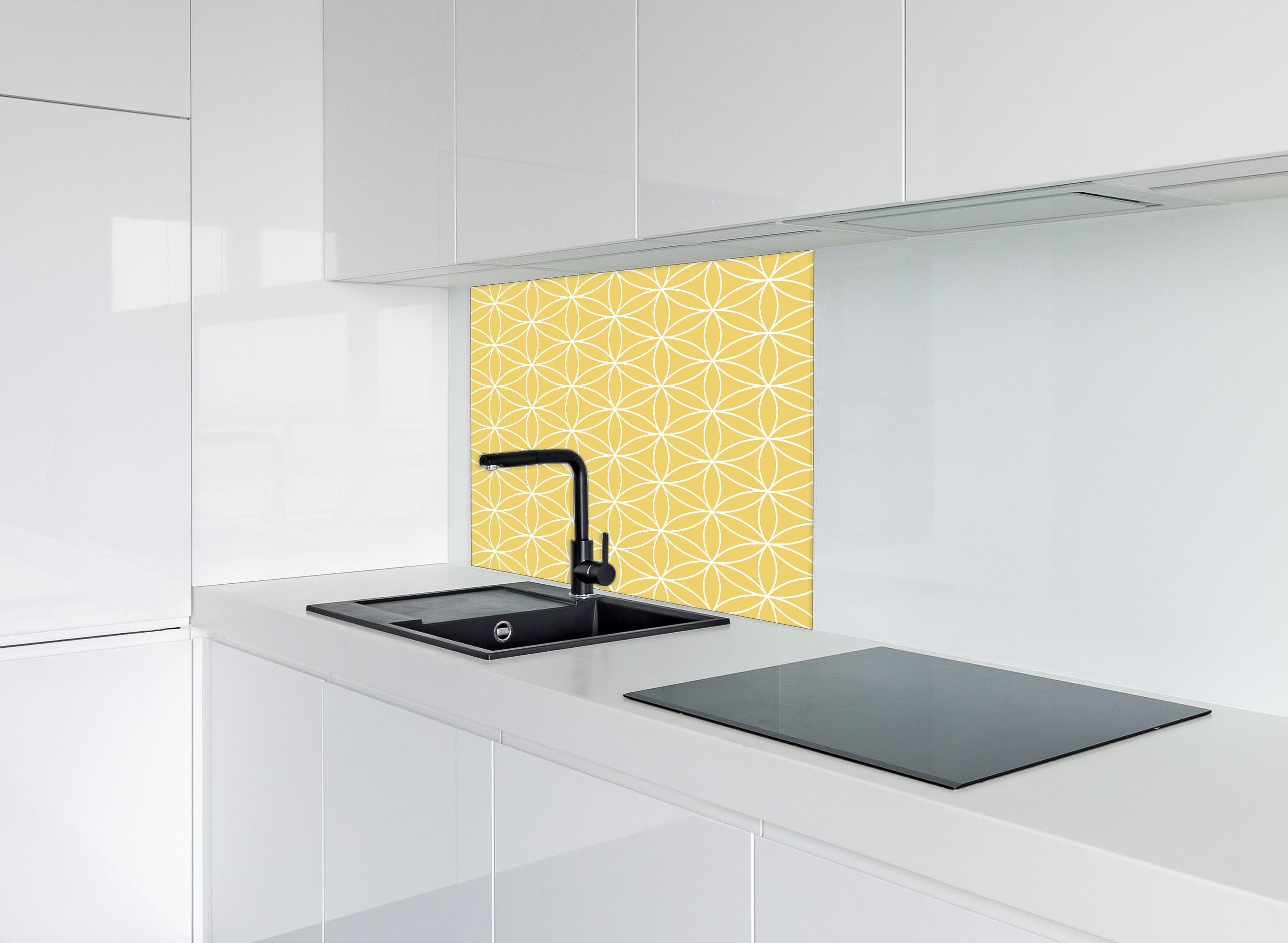 Spritzschutz - Geometrica Fiori Oro hinter einem Cerankochfeld zwischen Holz-Kochutensilien
