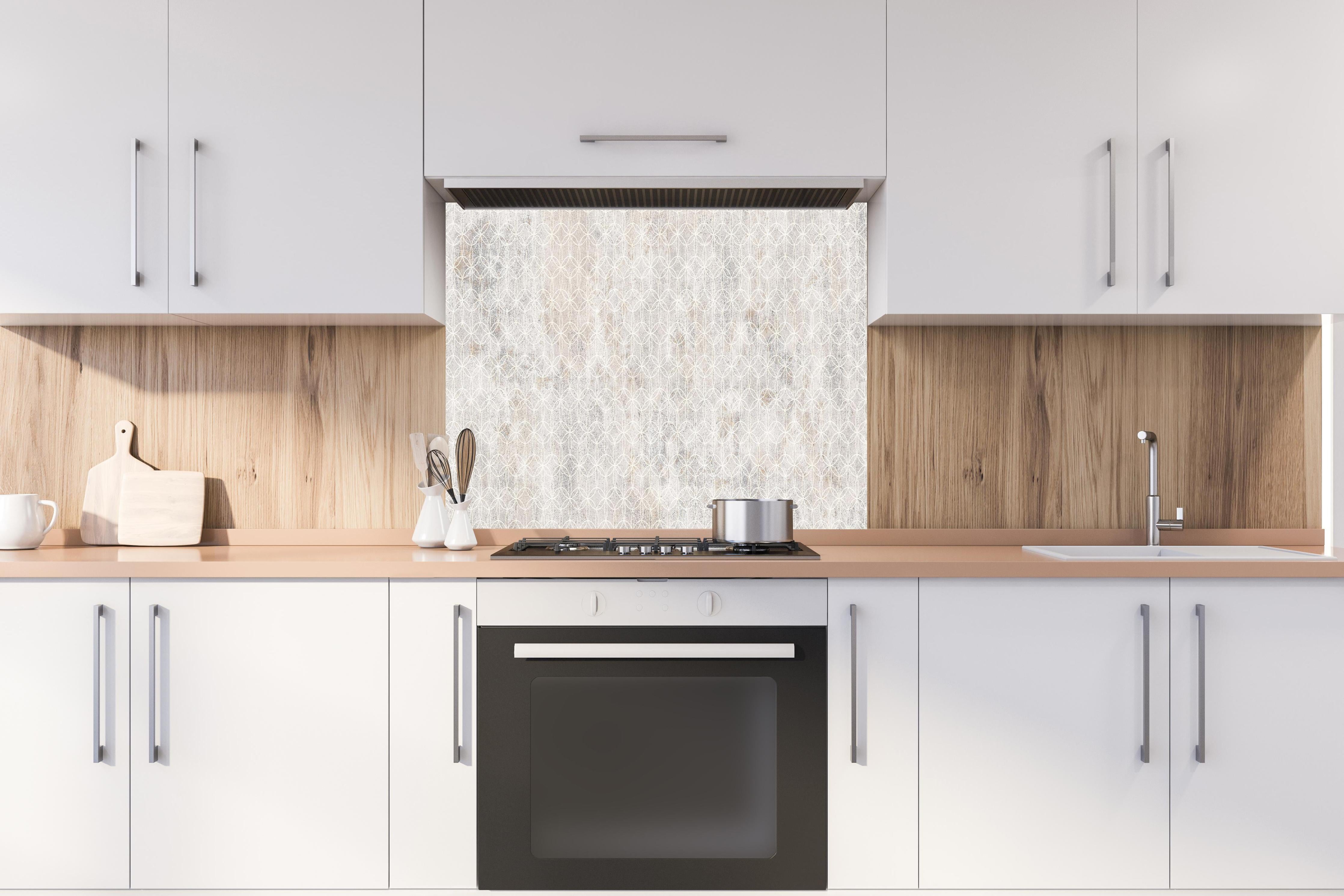 Spritzschutz - Geometrisches Beton Mosaik hinter einem Cerankochfeld zwischen Holz-Kochutensilien
