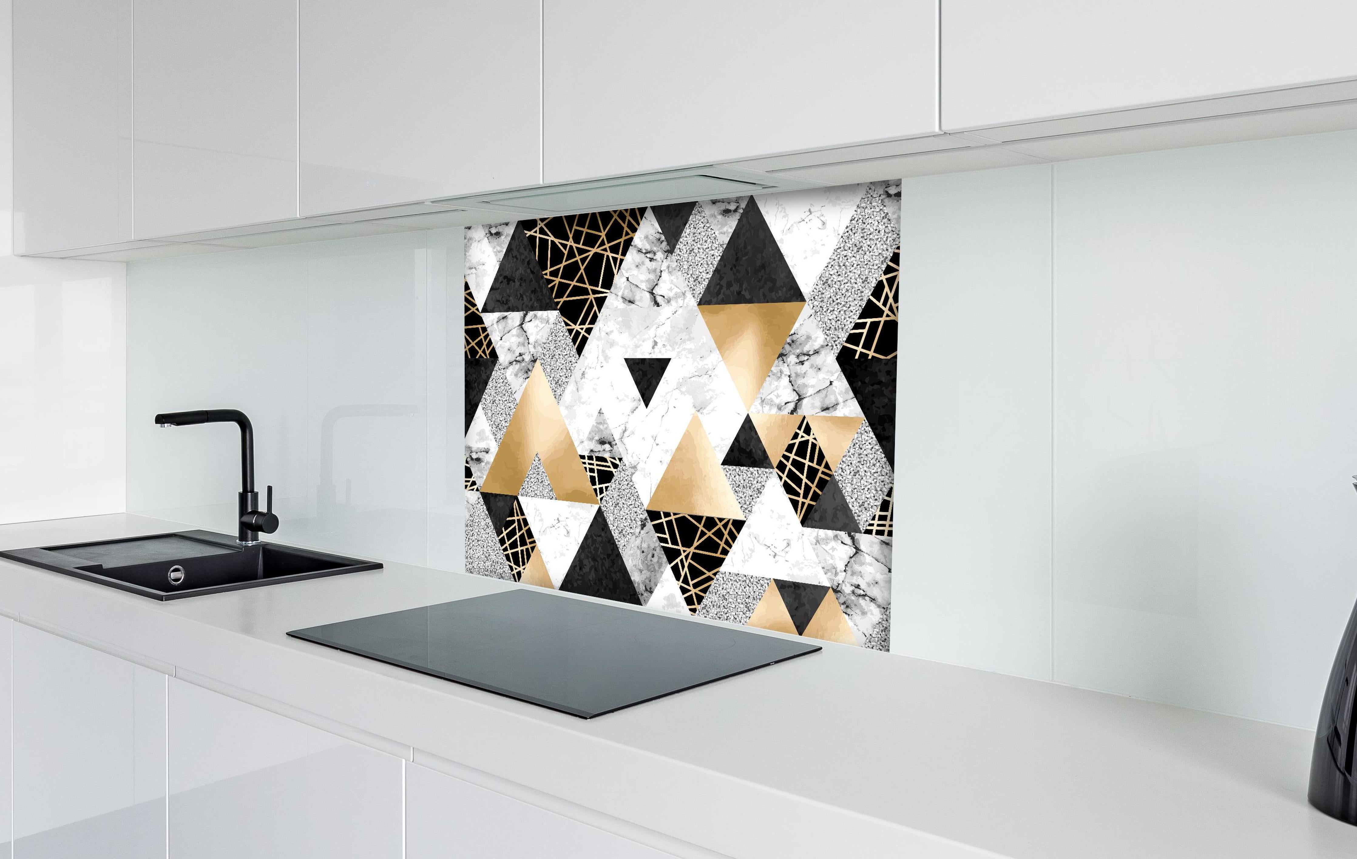 Spritzschutz - Geometrisches Muster in Gold, Schwarz und Weiß hinter einem Cerankochfeld zwischen Holz-Kochutensilien
