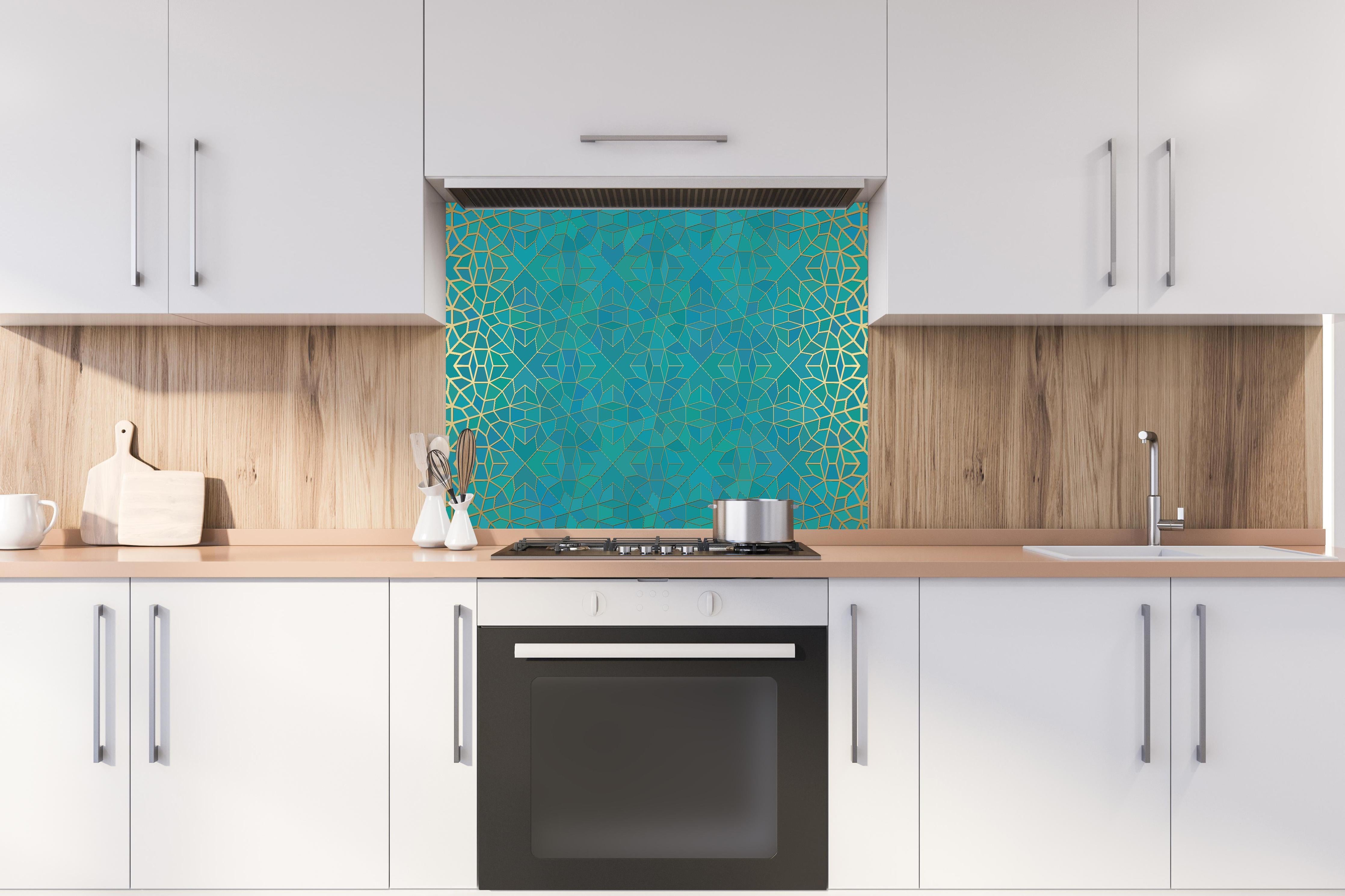 Spritzschutz - Geometrisches Muster mit Blauverlauf hinter einem Cerankochfeld zwischen Holz-Kochutensilien
