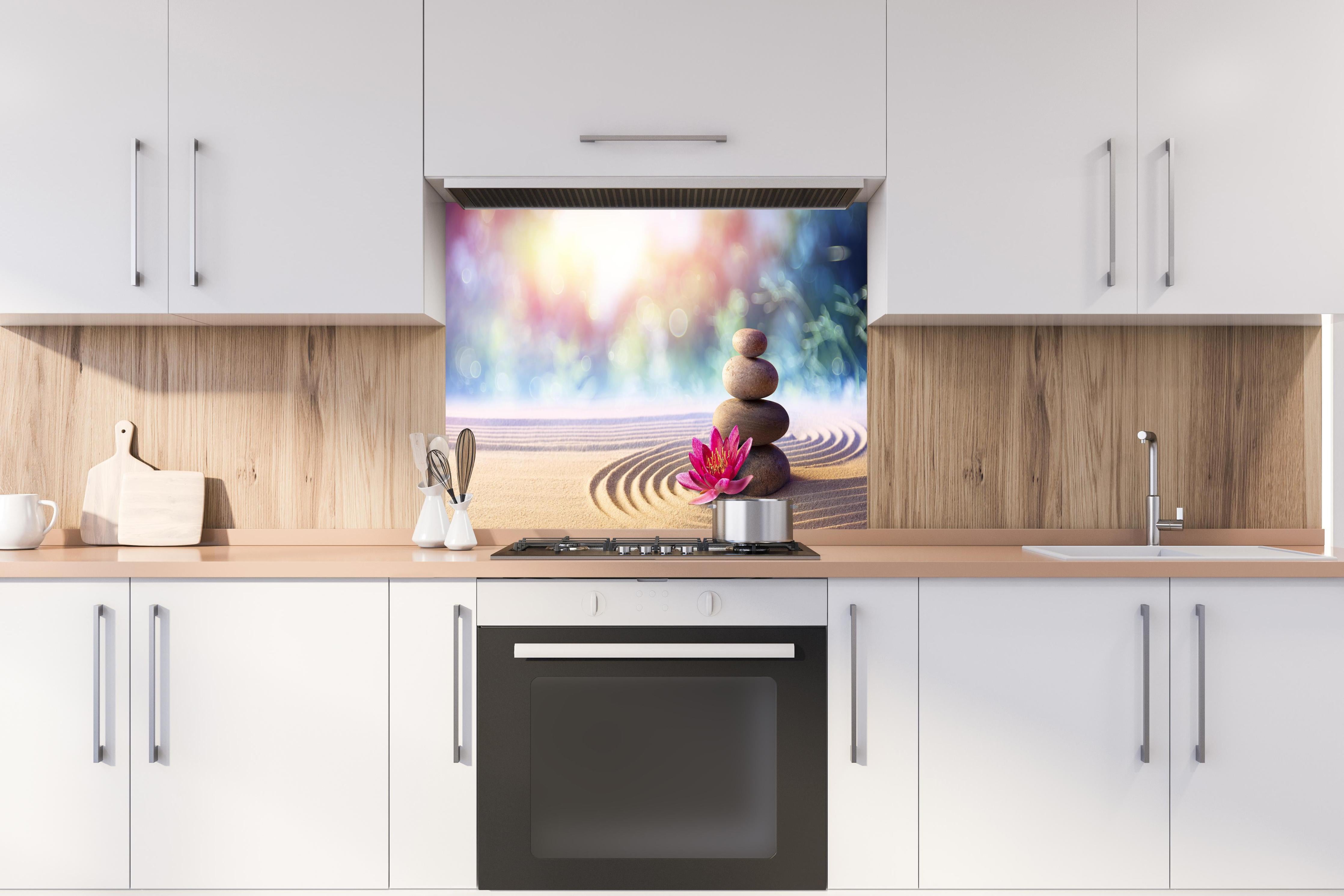 Spritzschutz - Gestapelte Meditation Steine hinter einem Cerankochfeld zwischen Holz-Kochutensilien
