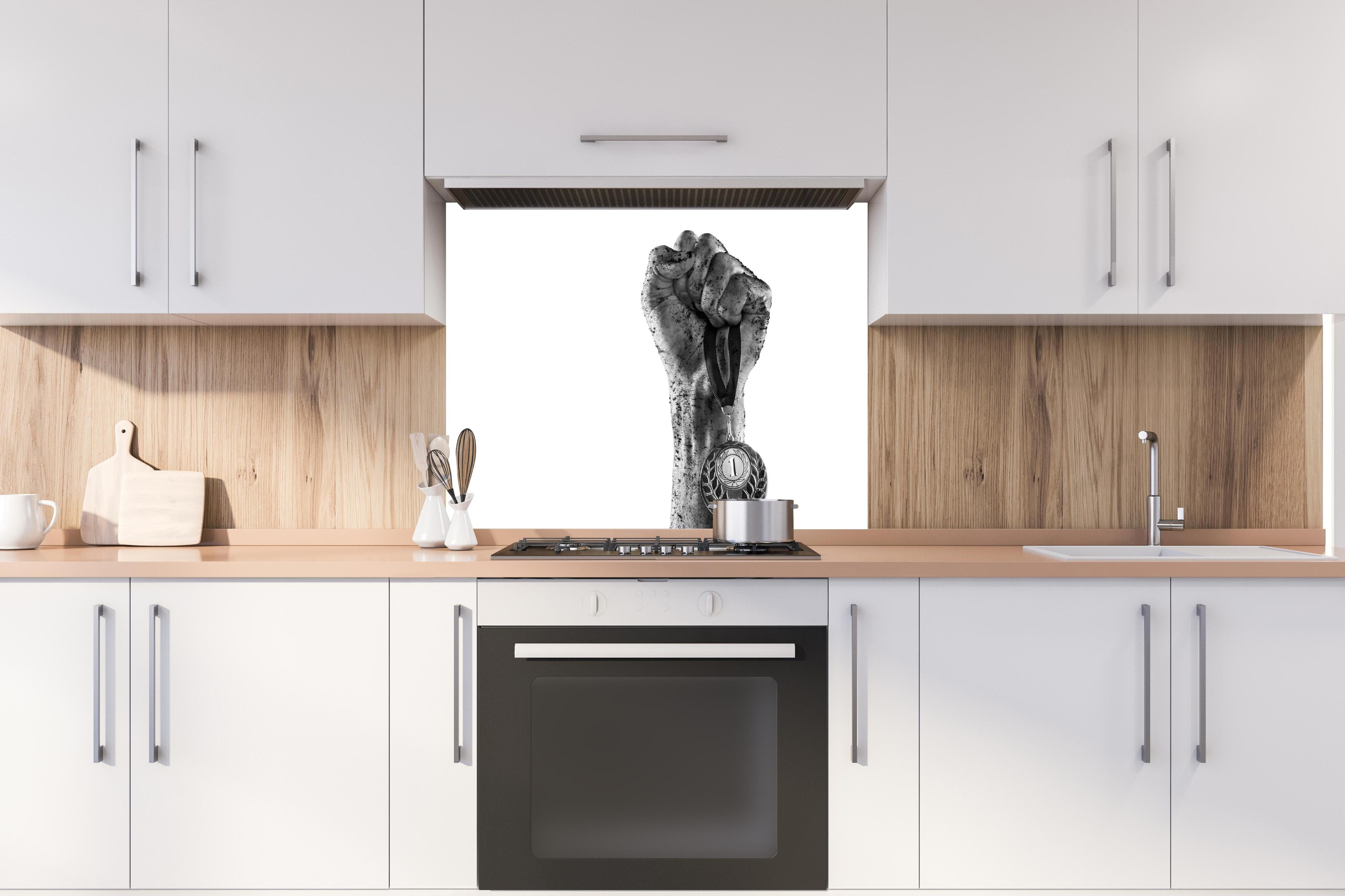 Spritzschutz - Gewinner mit einer Medaille hinter einem Cerankochfeld zwischen Holz-Kochutensilien
