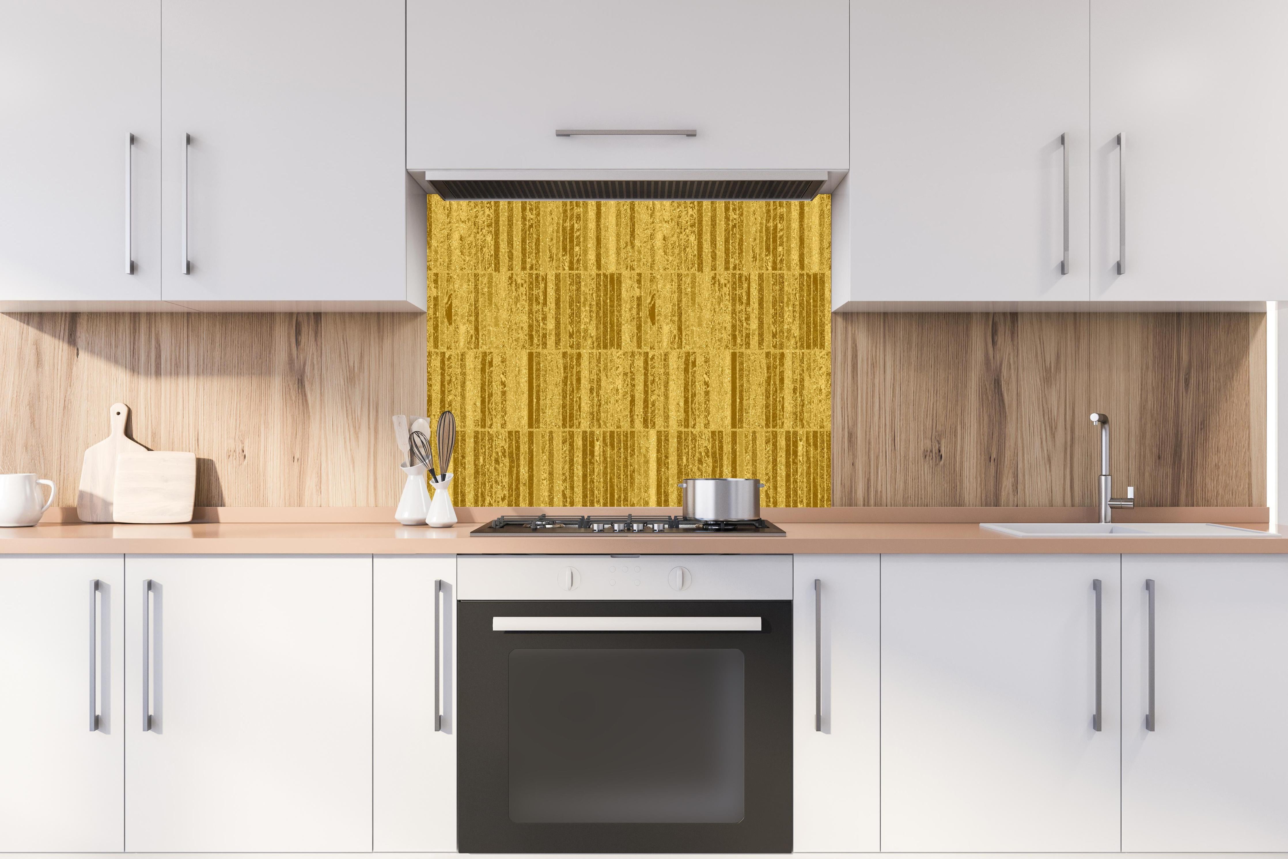 Spritzschutz - Glitzernde Gold Textur hinter einem Cerankochfeld zwischen Holz-Kochutensilien
