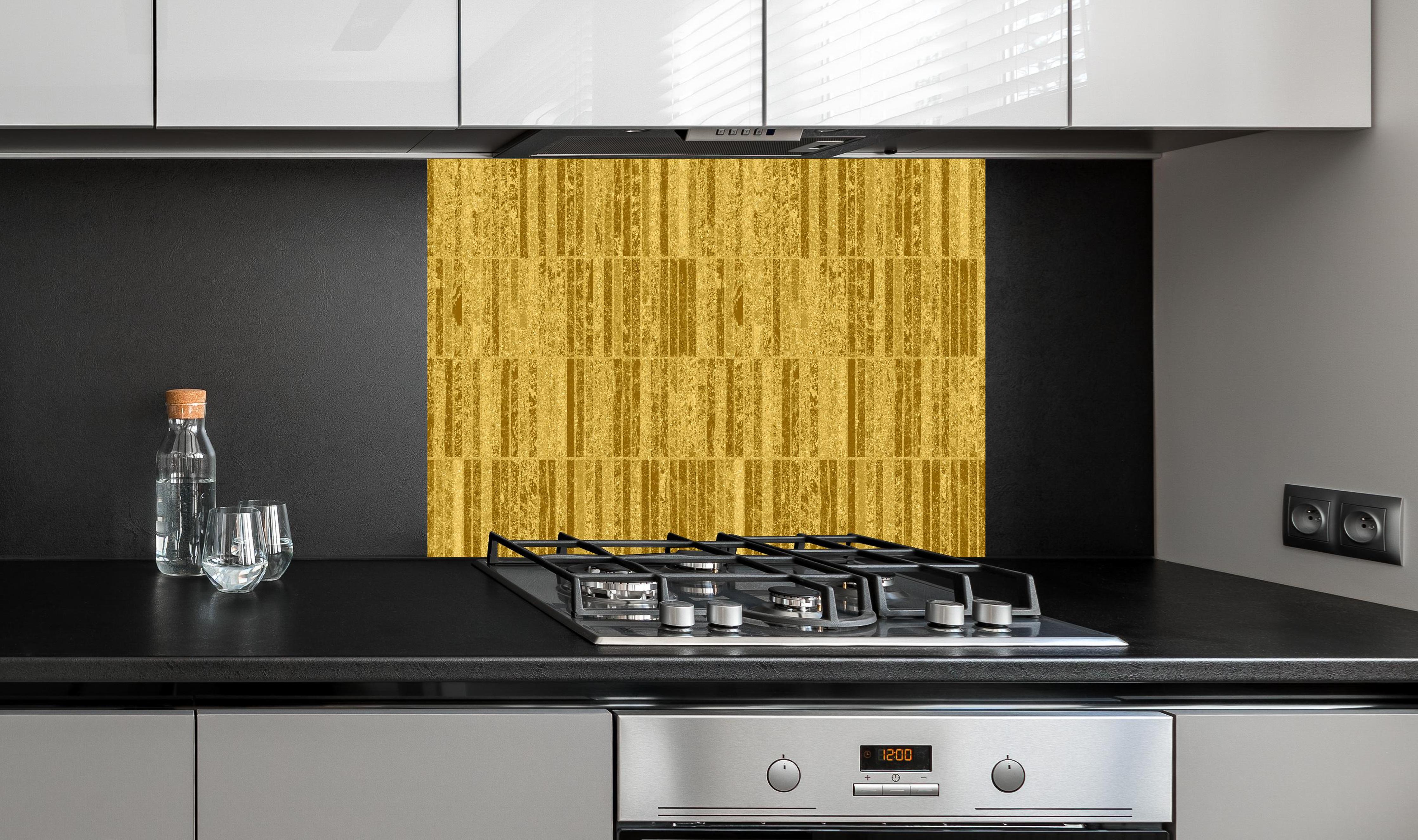 Spritzschutz - Glitzernde Gold Textur hinter einem Cerankochfeld zwischen Holz-Kochutensilien
