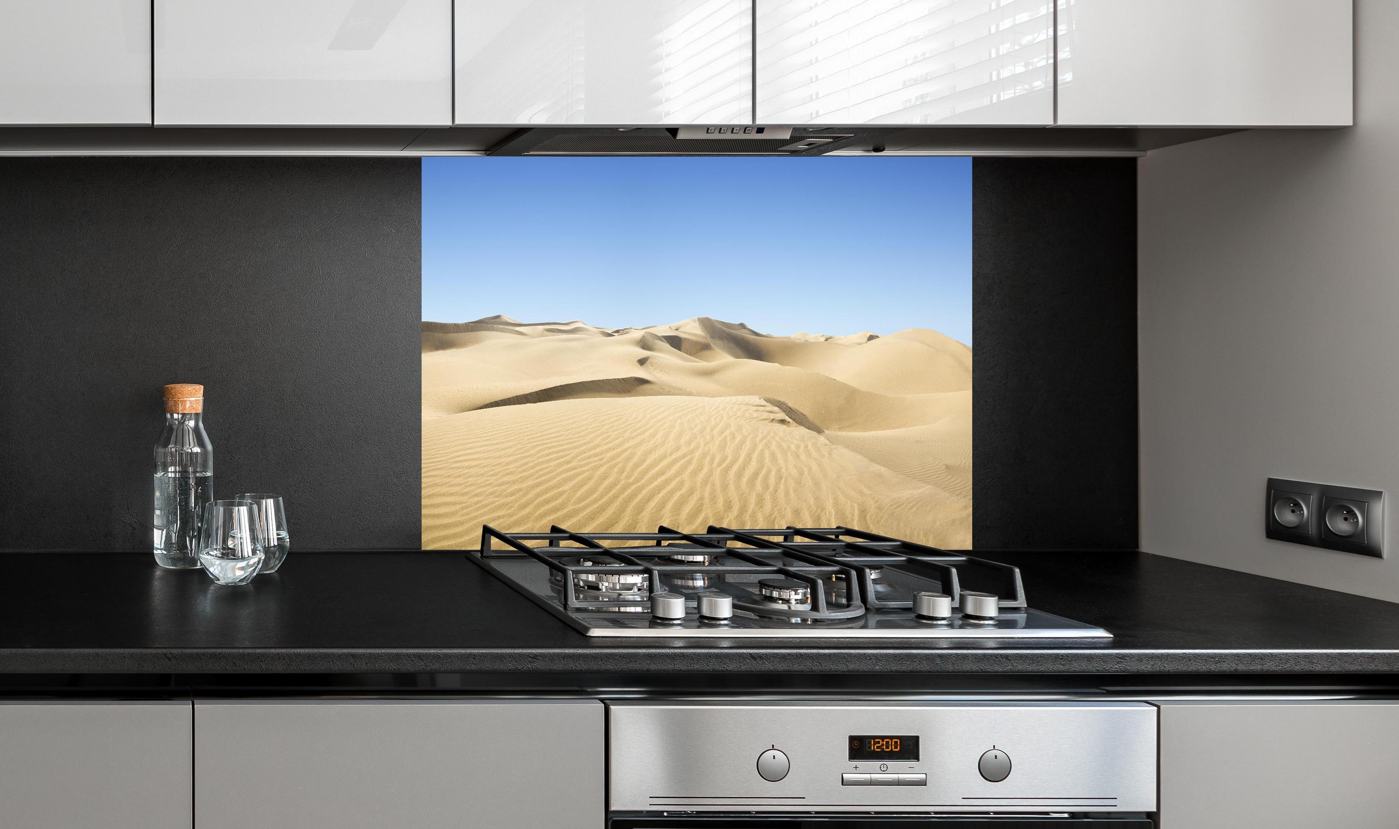 Spritzschutz - Gold desert hinter einem Cerankochfeld zwischen Holz-Kochutensilien
