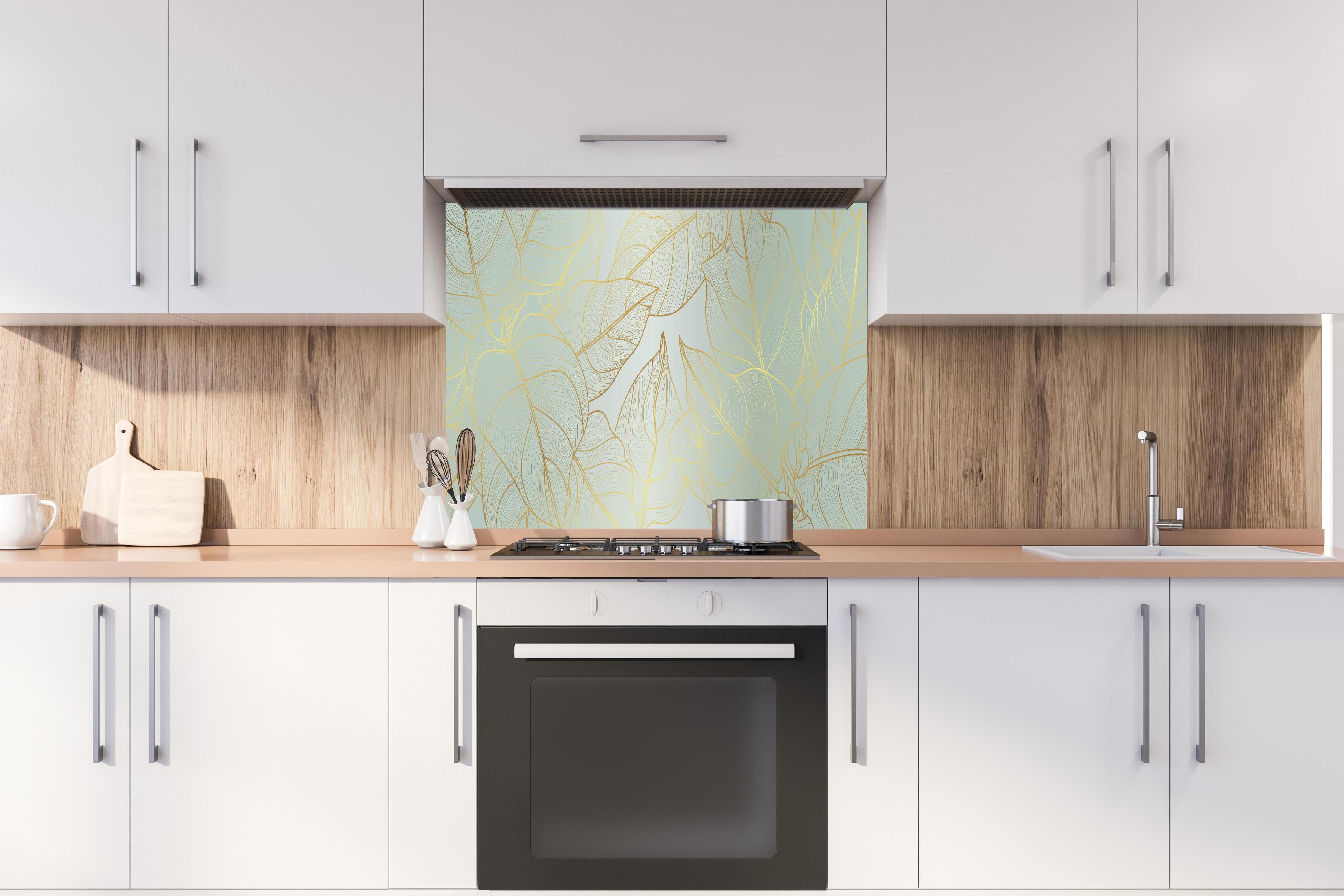 Spritzschutz - Goldener Blatt-Design Hintergrund hinter einem Cerankochfeld zwischen Holz-Kochutensilien
