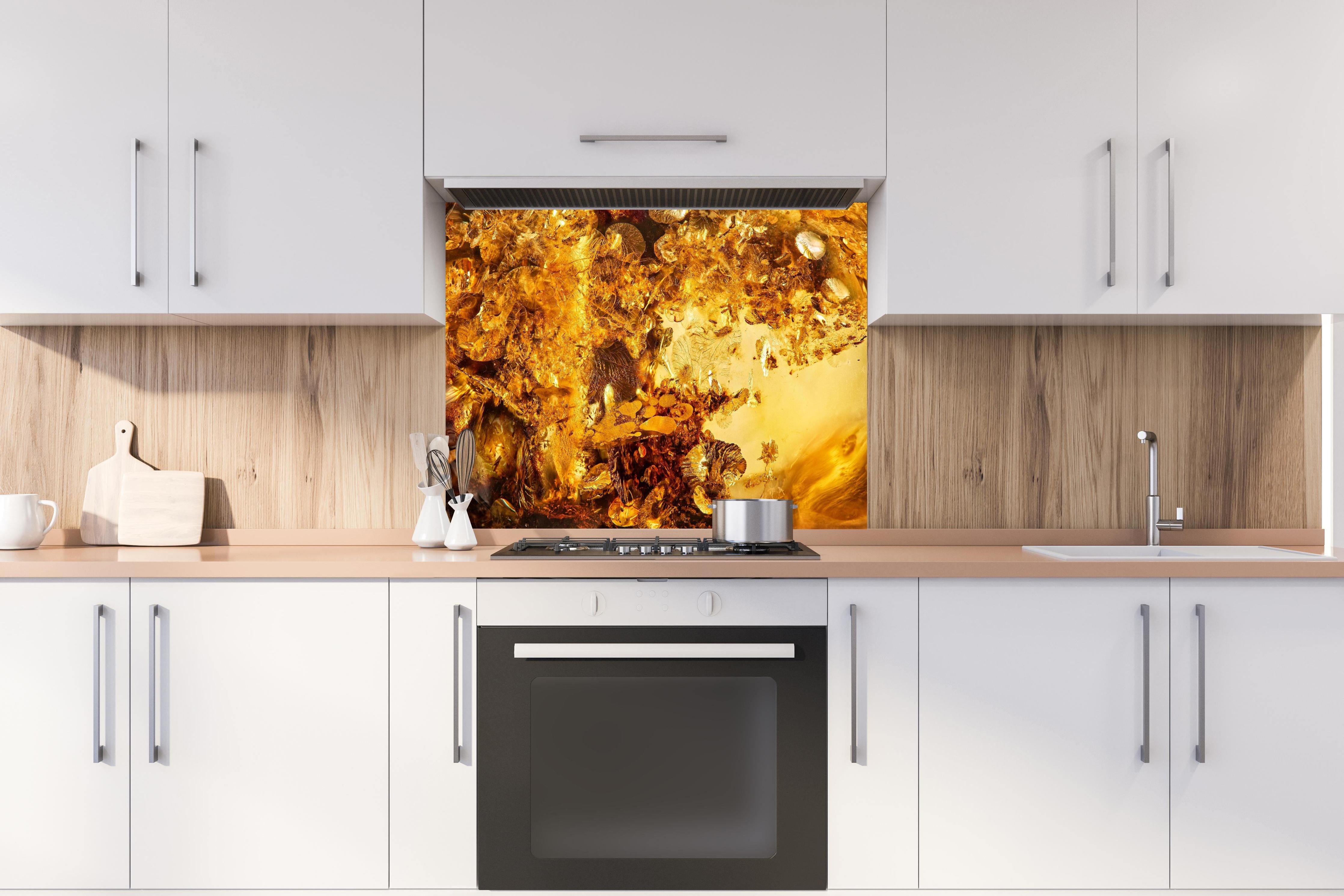 Spritzschutz - Goldener Kristall - Sonnenstein hinter einem Cerankochfeld zwischen Holz-Kochutensilien
