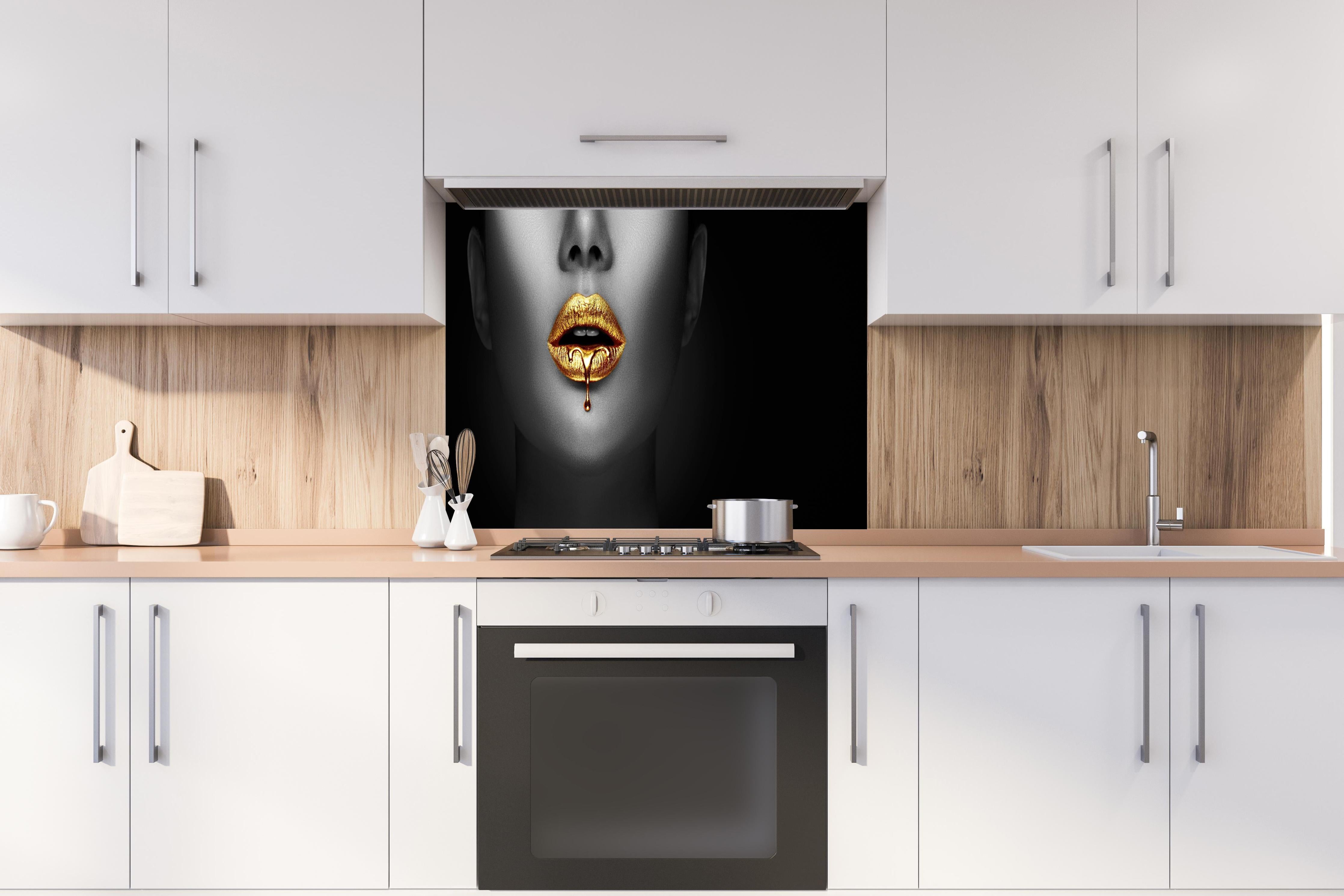 Spritzschutz - Goldener Lipgloss auf sexy Lippen Kunst hinter einem Cerankochfeld zwischen Holz-Kochutensilien
