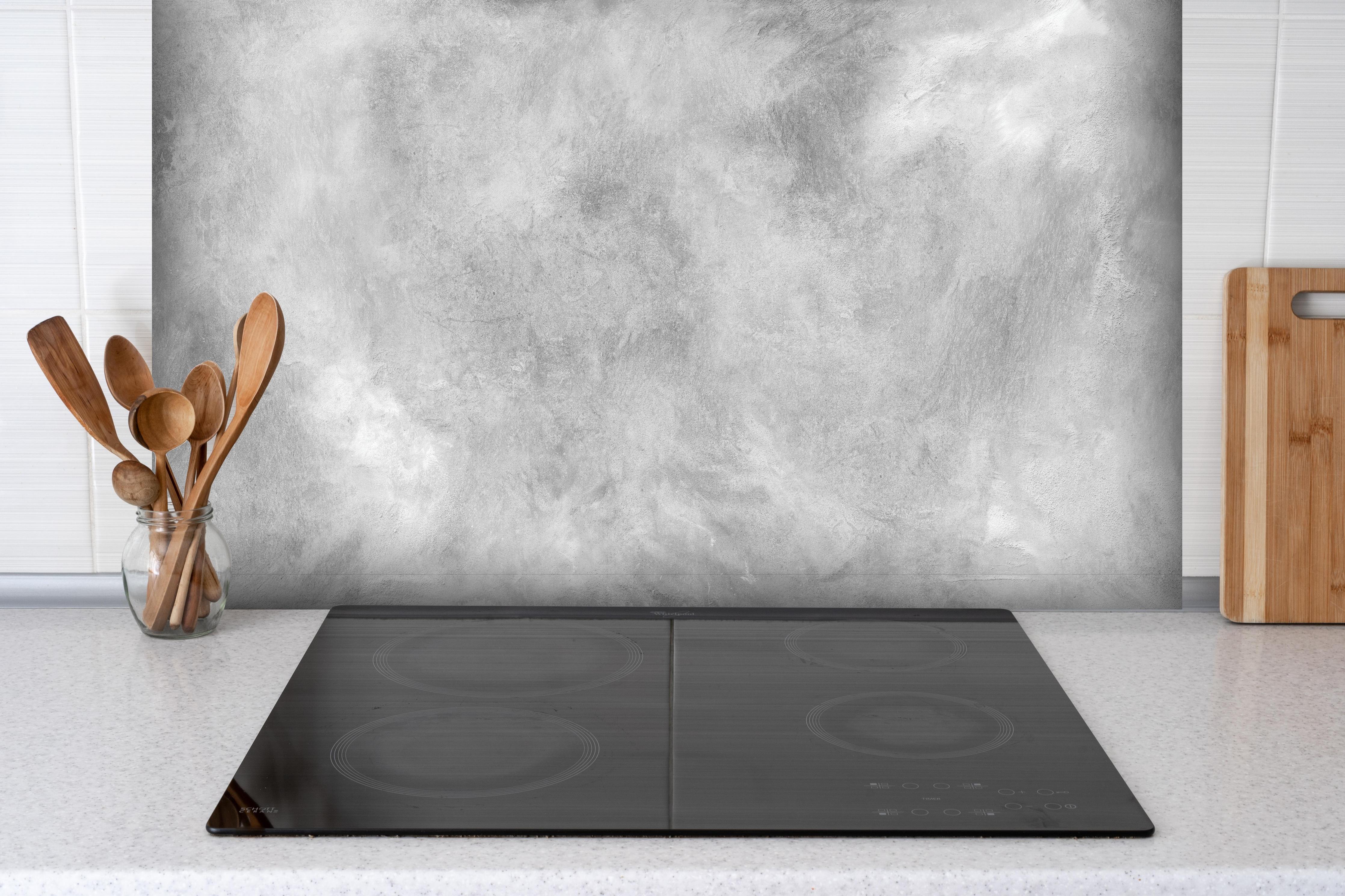 Spritzschutz - Gräuliches Marmor Design hinter einem Cerankochfeld zwischen Holz-Kochutensilien
