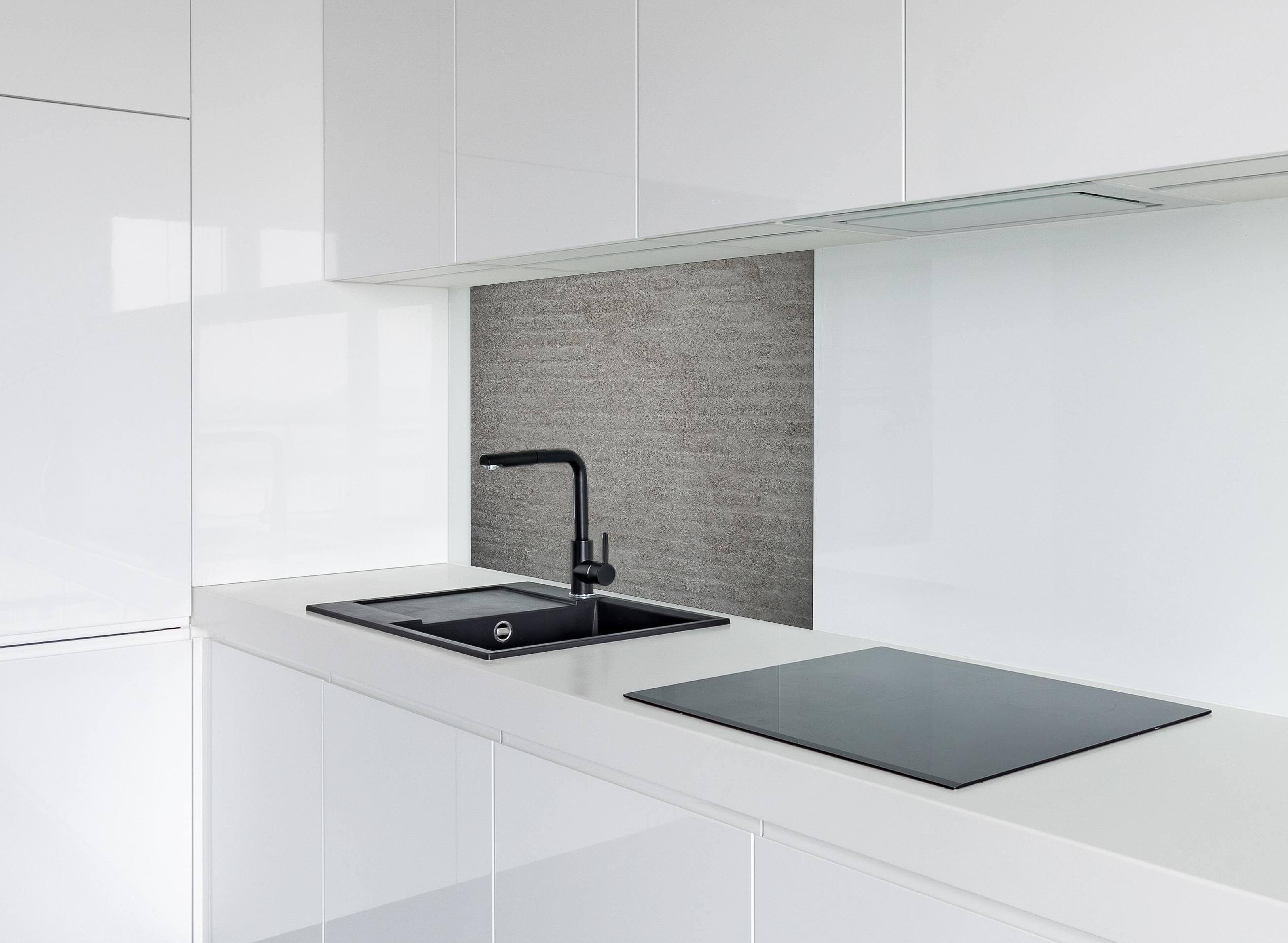 Spritzschutz - Gräuliches Mauerwerk hinter einem Cerankochfeld zwischen Holz-Kochutensilien
