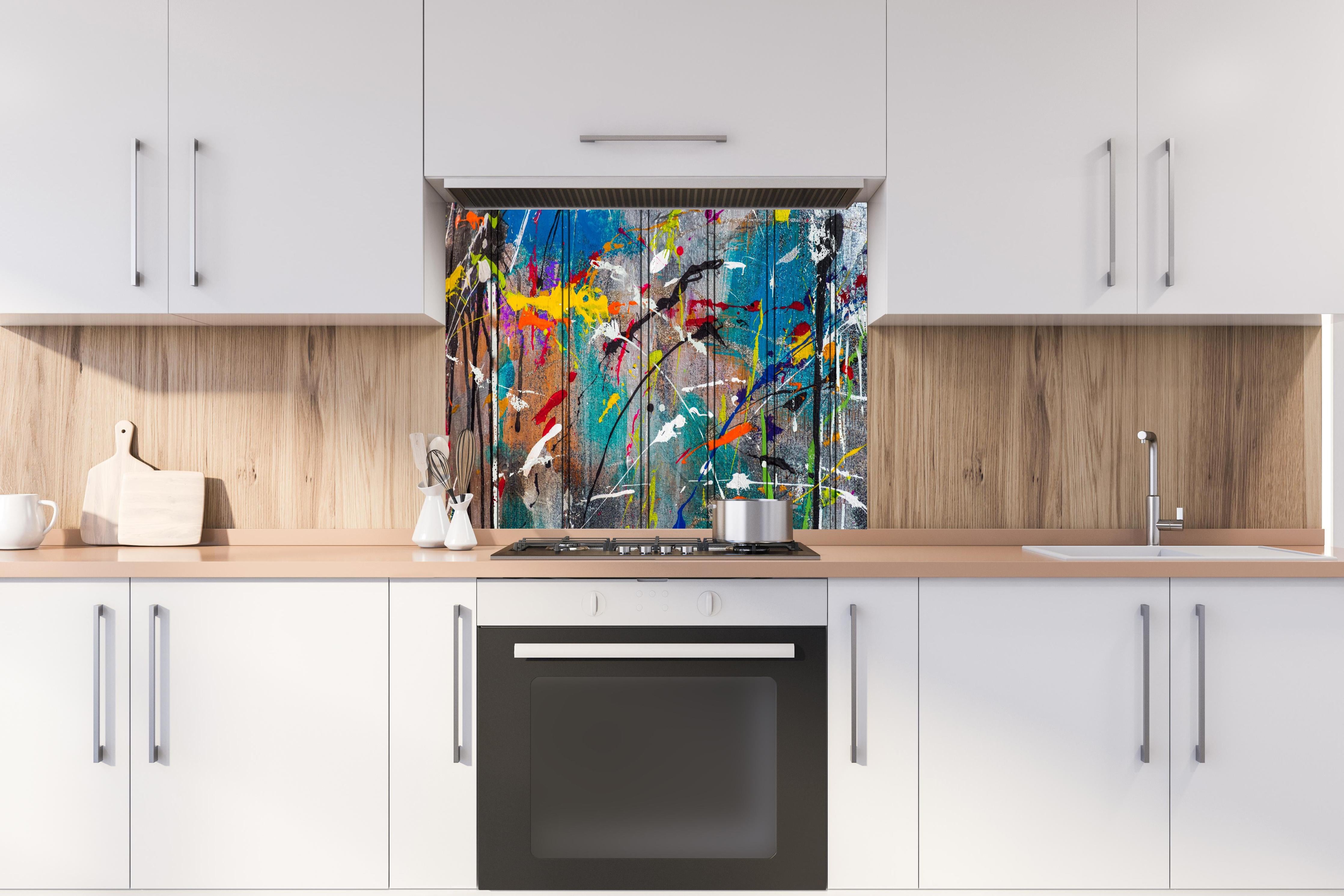 Spritzschutz - Graffiti auf Holz hinter einem Cerankochfeld zwischen Holz-Kochutensilien
