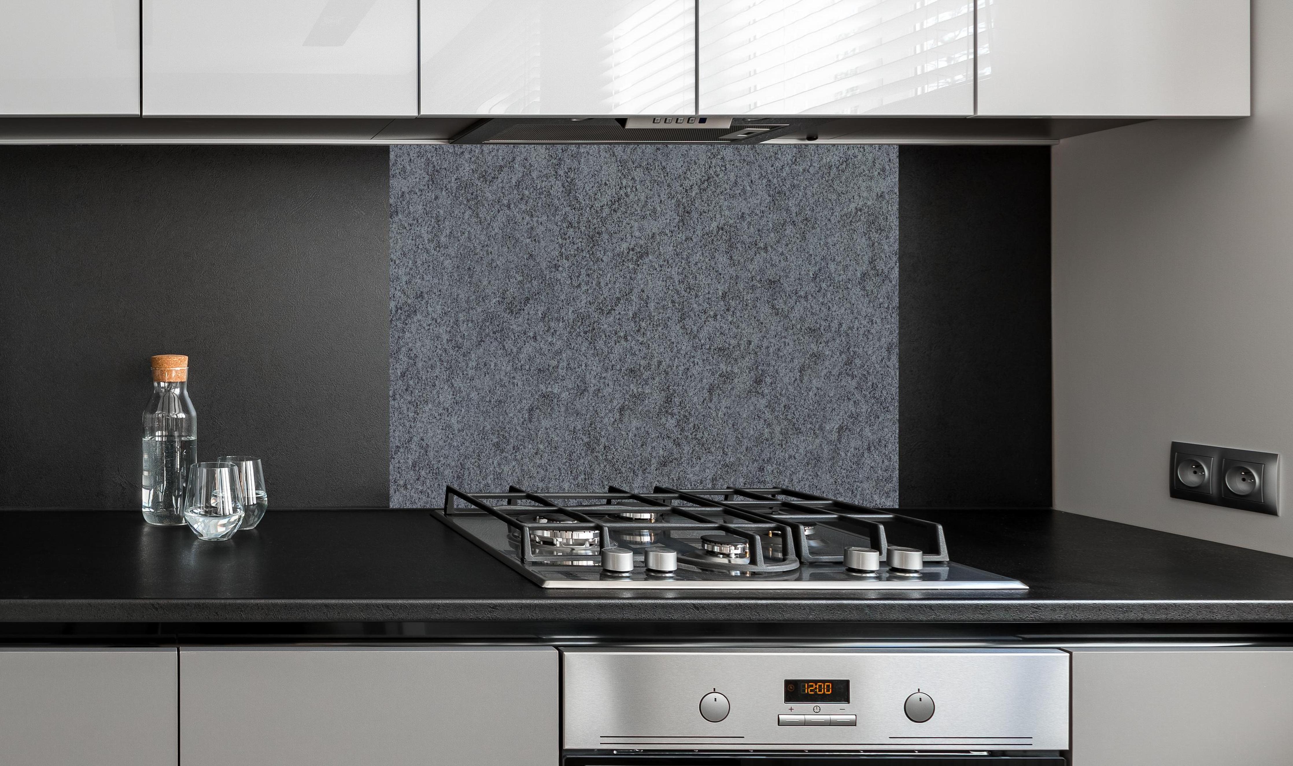 Spritzschutz - Granit Marmor Textur hinter einem Cerankochfeld zwischen Holz-Kochutensilien
