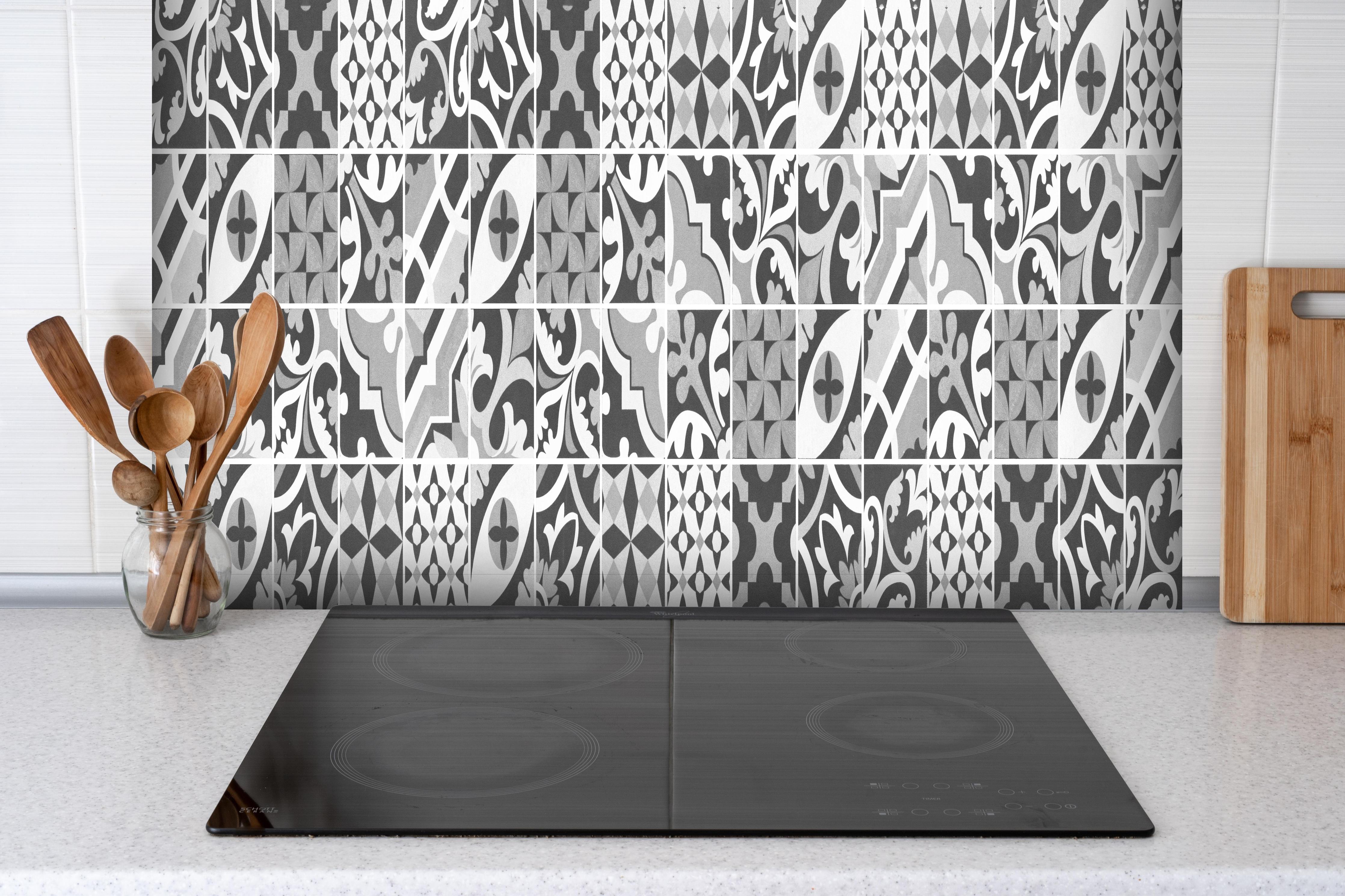 Spritzschutz - Grau-Weiß Vintage Mosaik hinter einem Cerankochfeld zwischen Holz-Kochutensilien
