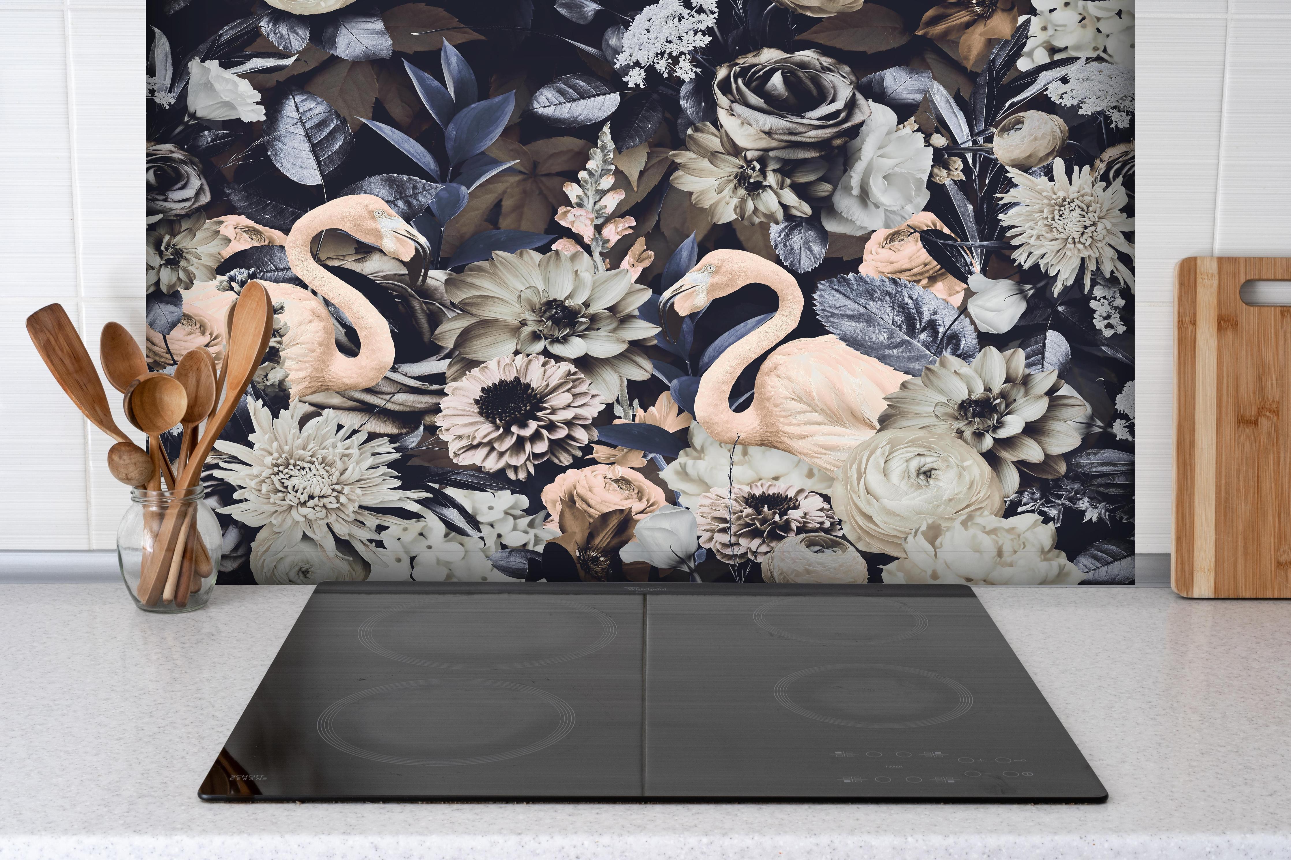 Spritzschutz - Grau-Weiße Flamingos im Blumenmeer hinter einem Cerankochfeld zwischen Holz-Kochutensilien
