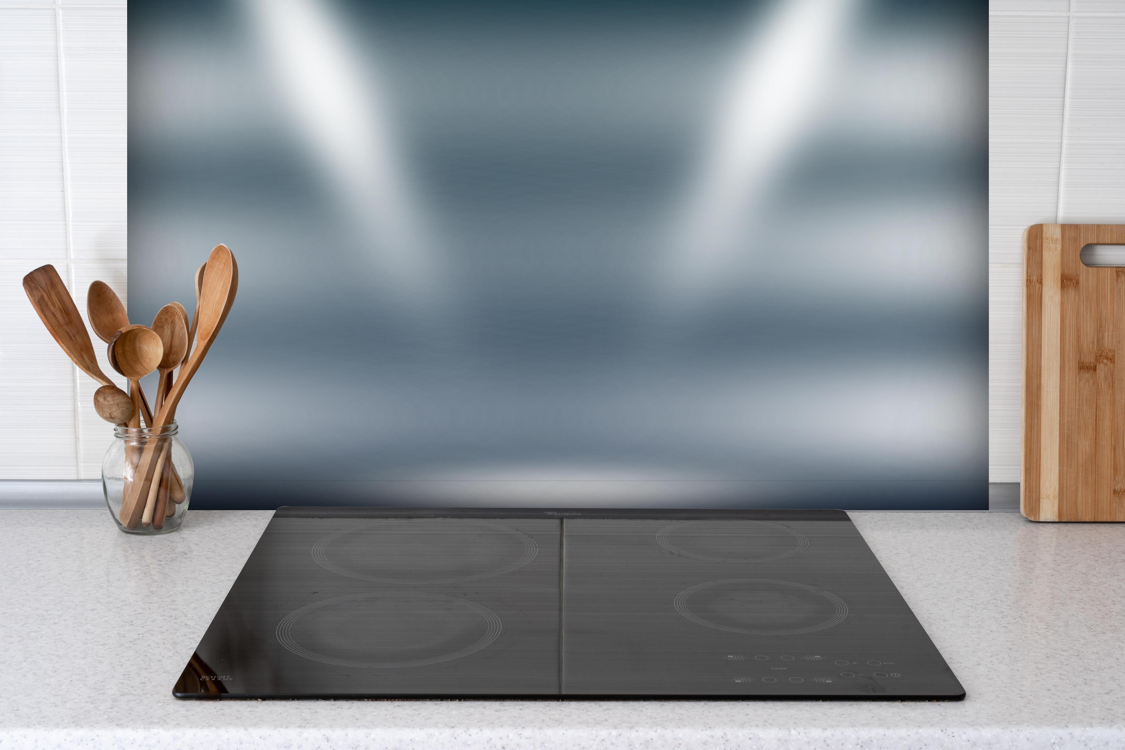 Spritzschutz - Grau-Weiße Leuchtende Abstraktion Hintergrund hinter einem Cerankochfeld zwischen Holz-Kochutensilien
