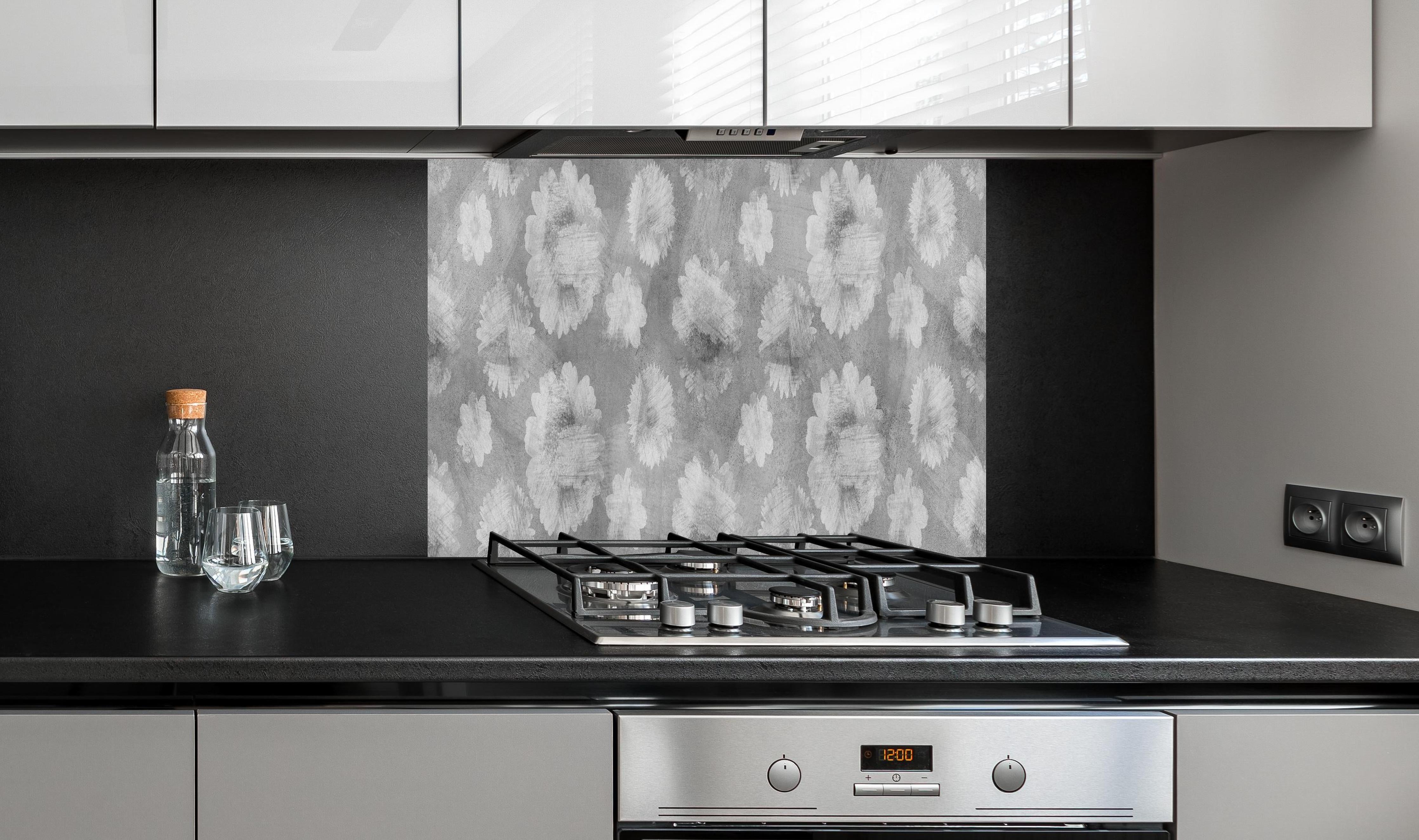 Spritzschutz - Graue Zement Wand mit weißem Blumenmuster hinter einem Cerankochfeld zwischen Holz-Kochutensilien
