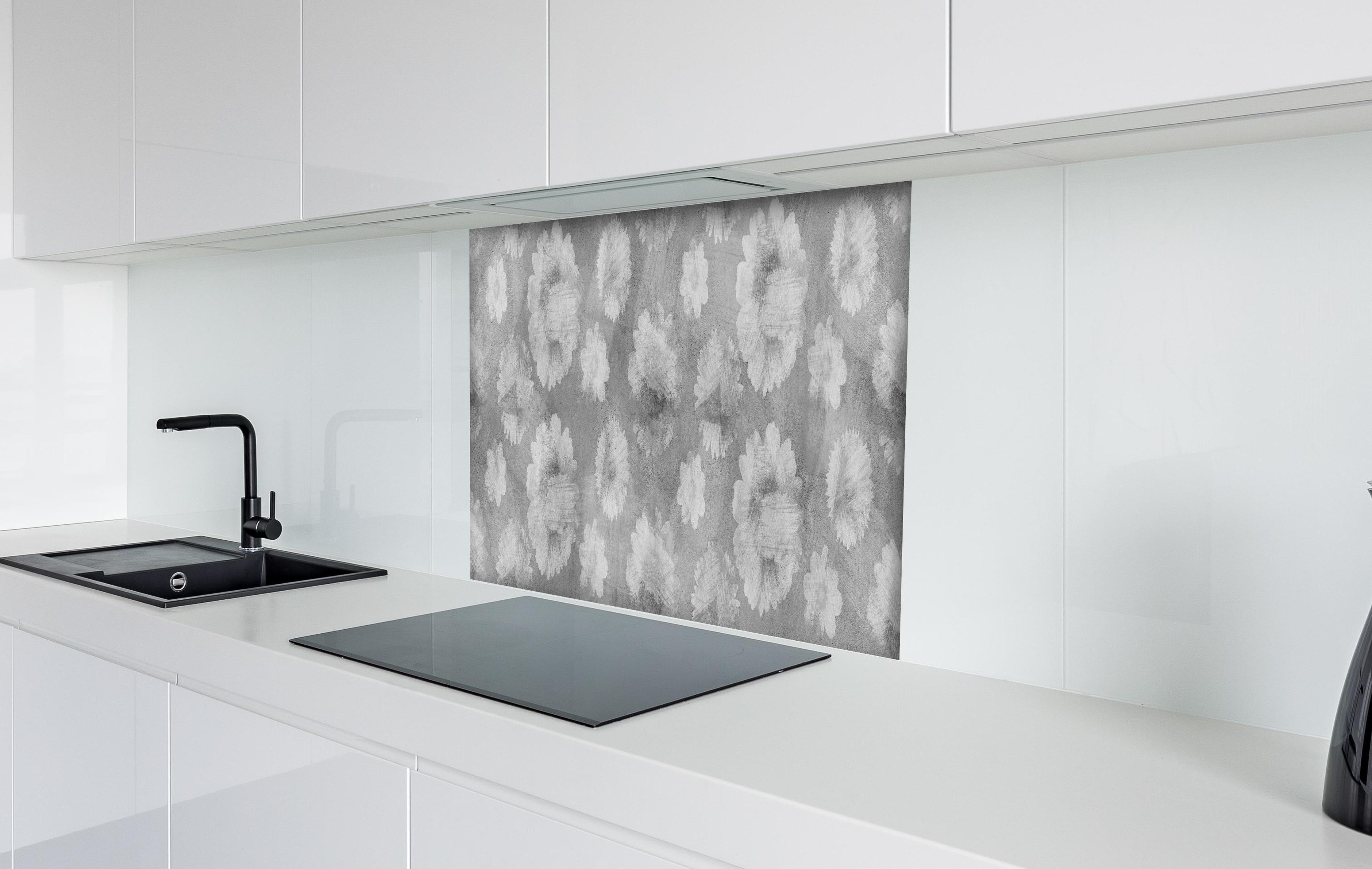 Spritzschutz - Graue Zement Wand mit weißem Blumenmuster hinter einem Cerankochfeld zwischen Holz-Kochutensilien
