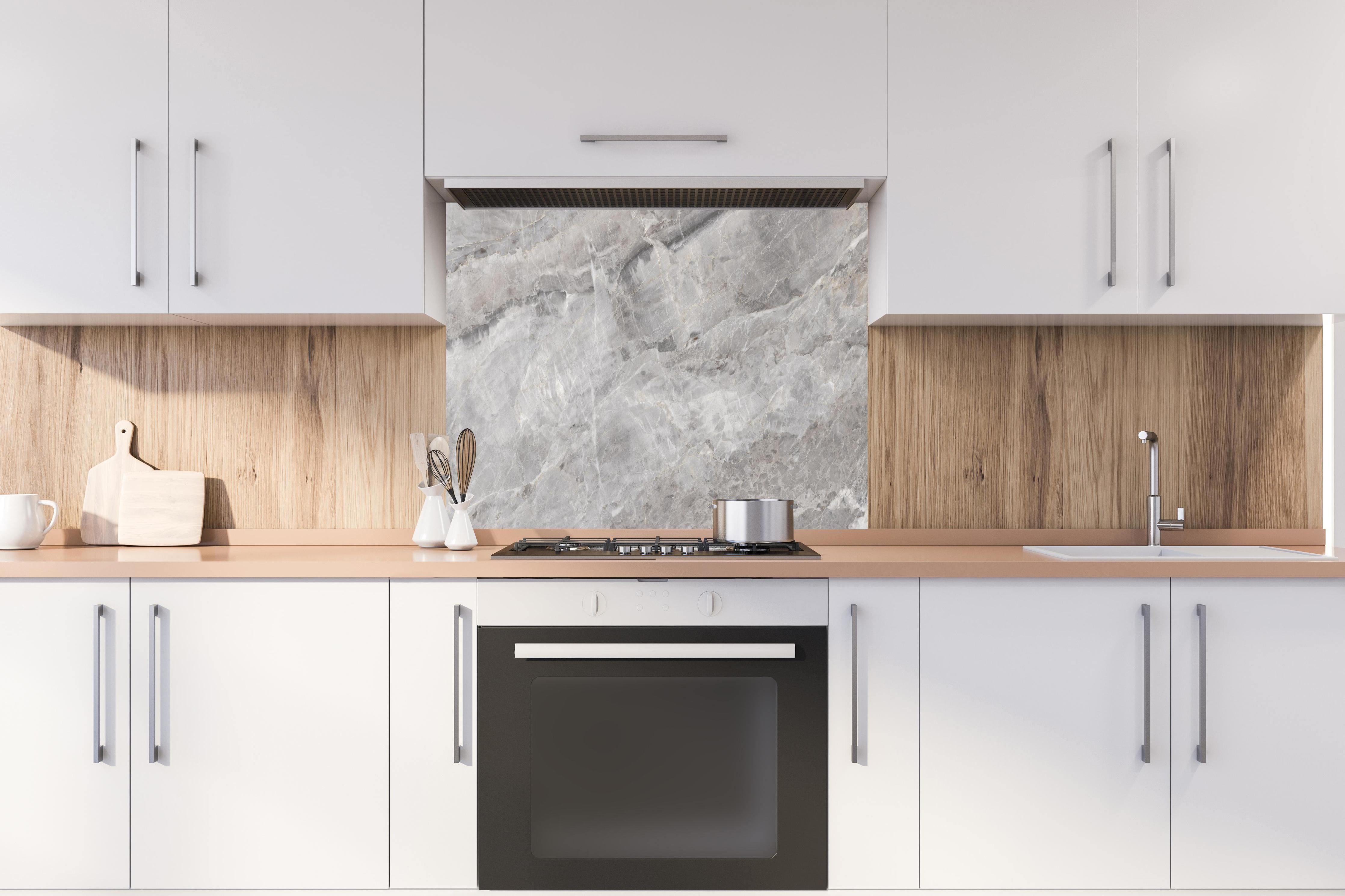 Spritzschutz - Grauer Marmor - Granit hinter einem Cerankochfeld zwischen Holz-Kochutensilien
