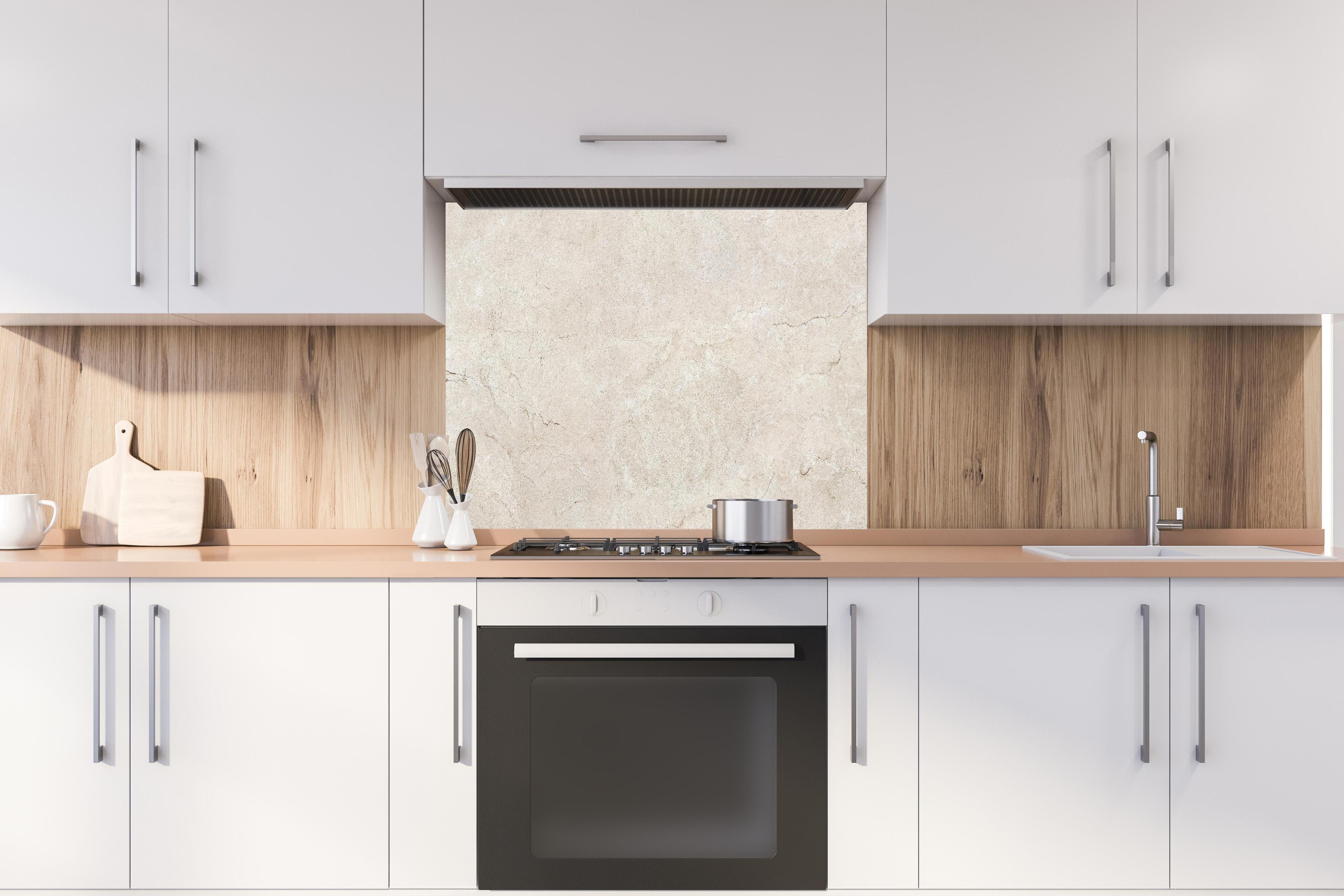 Spritzschutz - Grauer Marmor auf steinigem Hintergrund hinter einem Cerankochfeld zwischen Holz-Kochutensilien
