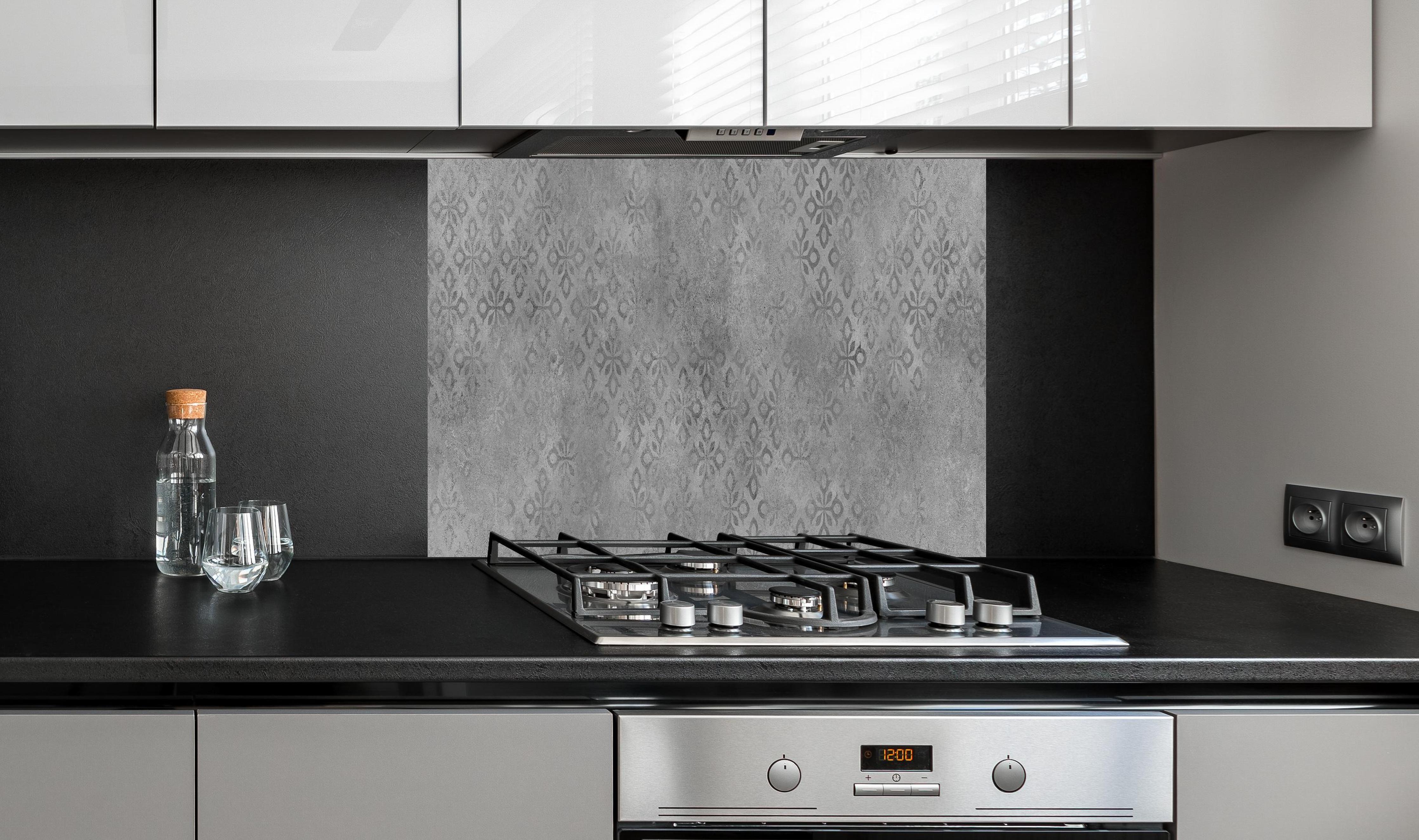 Spritzschutz - Graues Ornament Muster  hinter einem Cerankochfeld zwischen Holz-Kochutensilien
