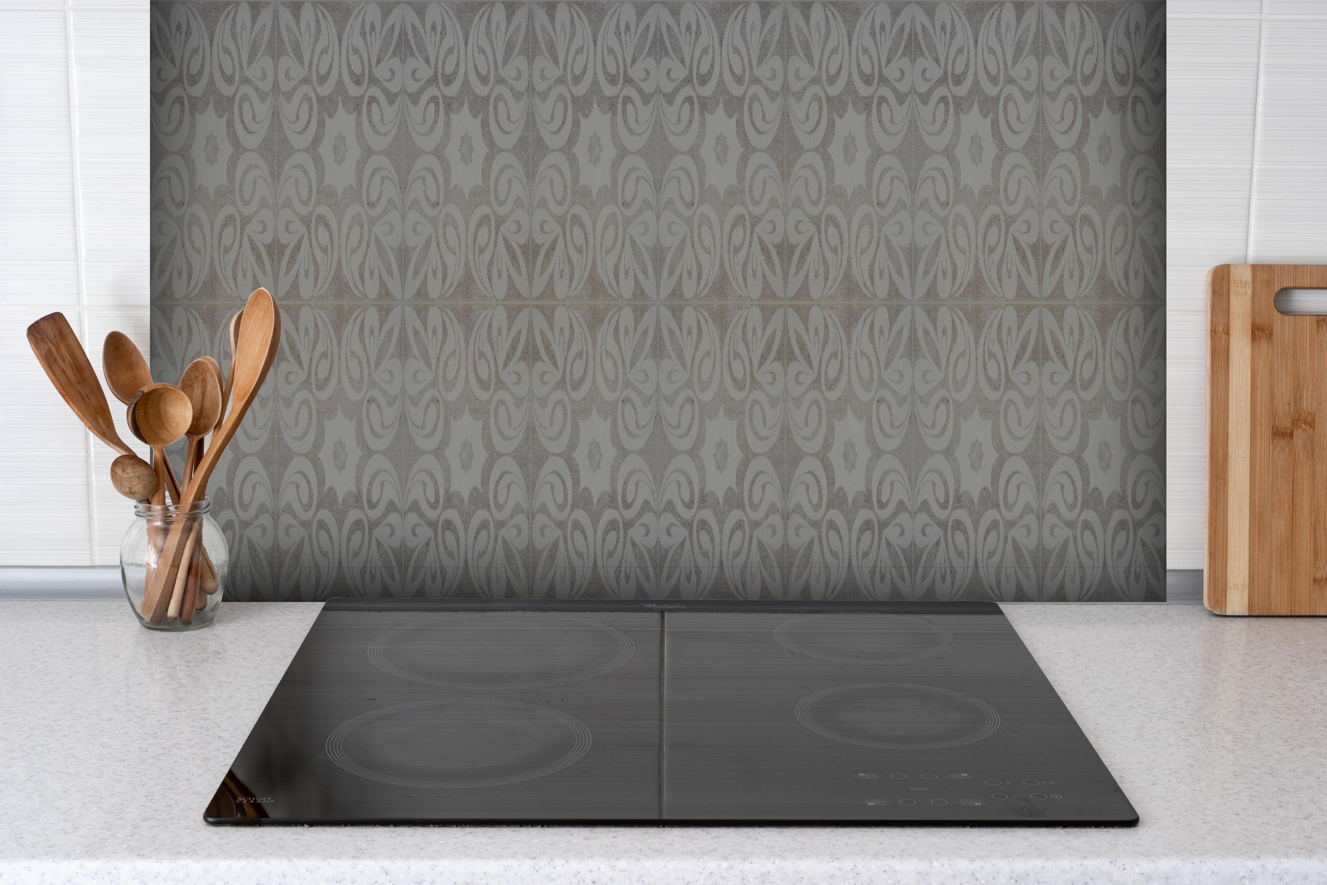 Spritzschutz - Graues quadratisches Mosaikmotiv hinter einem Cerankochfeld zwischen Holz-Kochutensilien
