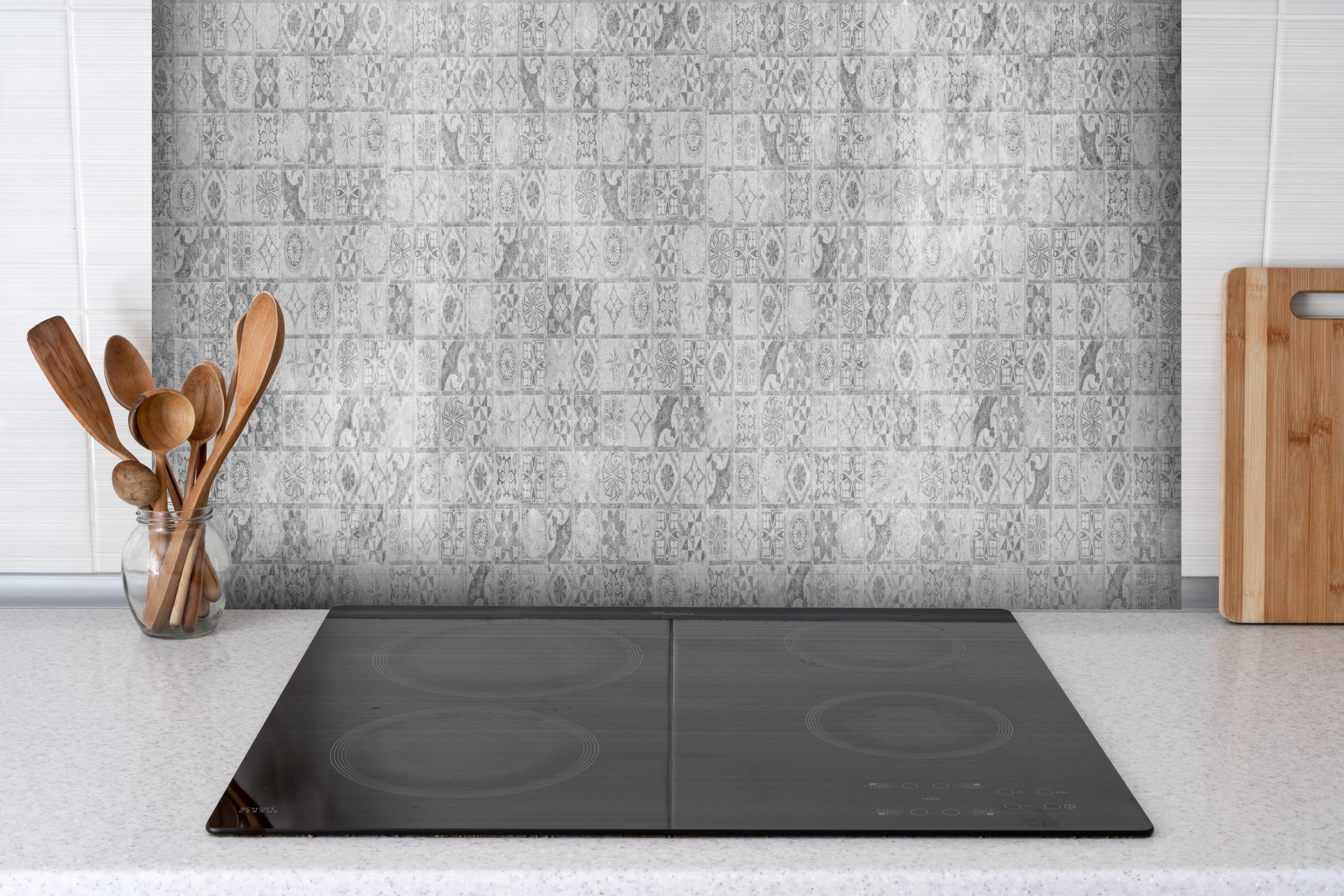 Spritzschutz - Graues weißes Mosaikmotiv hinter einem Cerankochfeld zwischen Holz-Kochutensilien
