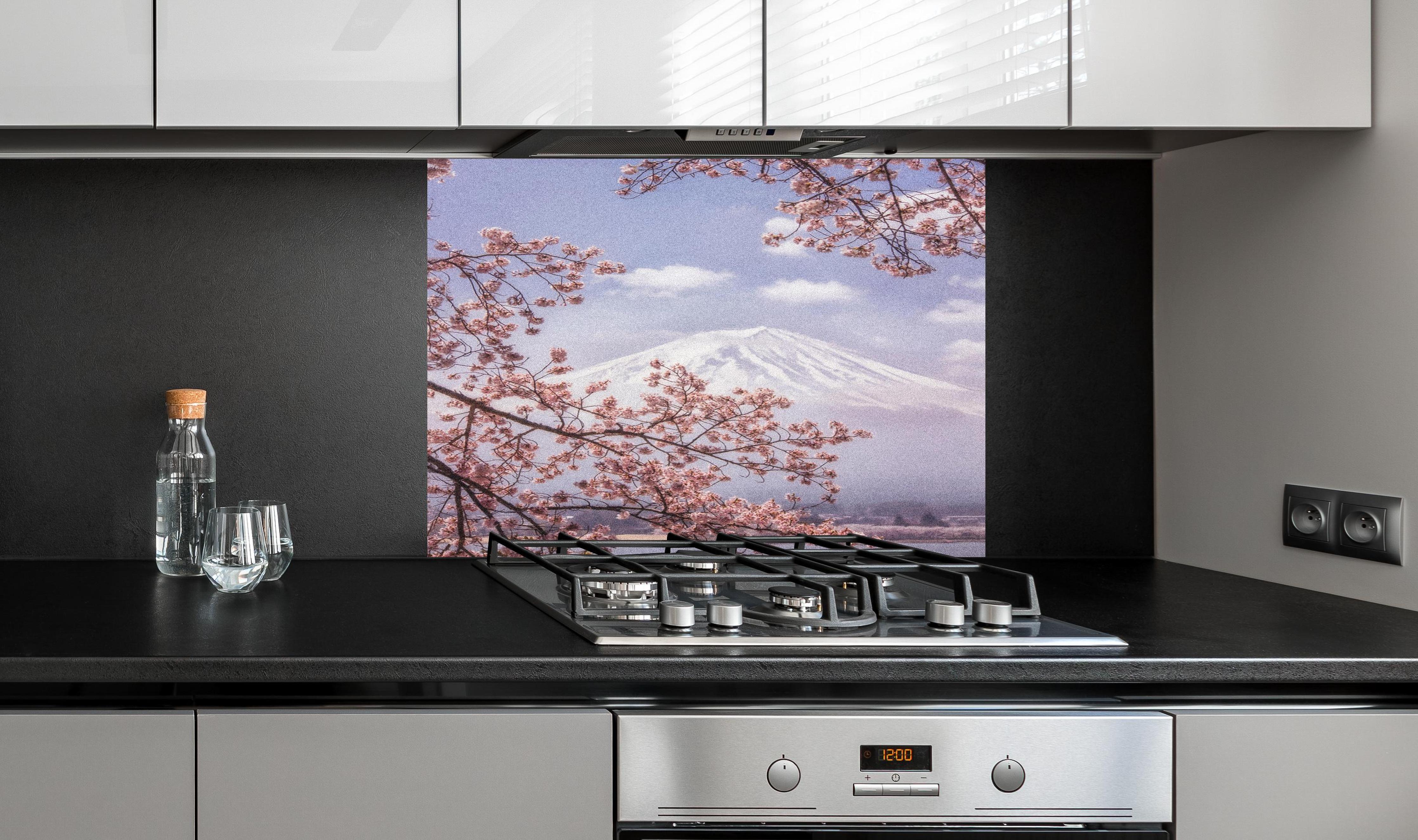 Spritzschutz - Großer Berg hinter Kirchblüten - Japan hinter einem Cerankochfeld zwischen Holz-Kochutensilien
