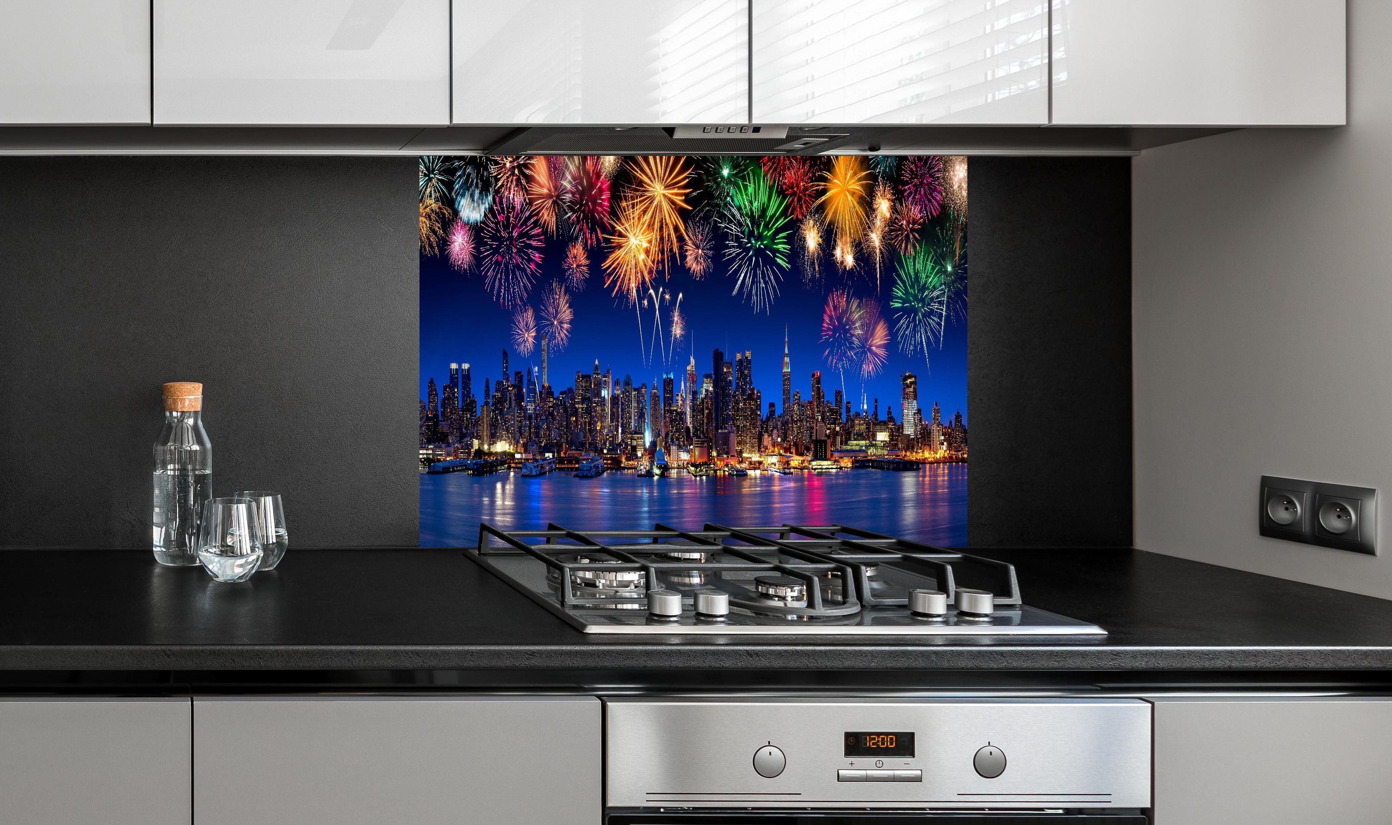 Spritzschutz - Großes Feuerwerk in New York hinter einem Cerankochfeld zwischen Holz-Kochutensilien
