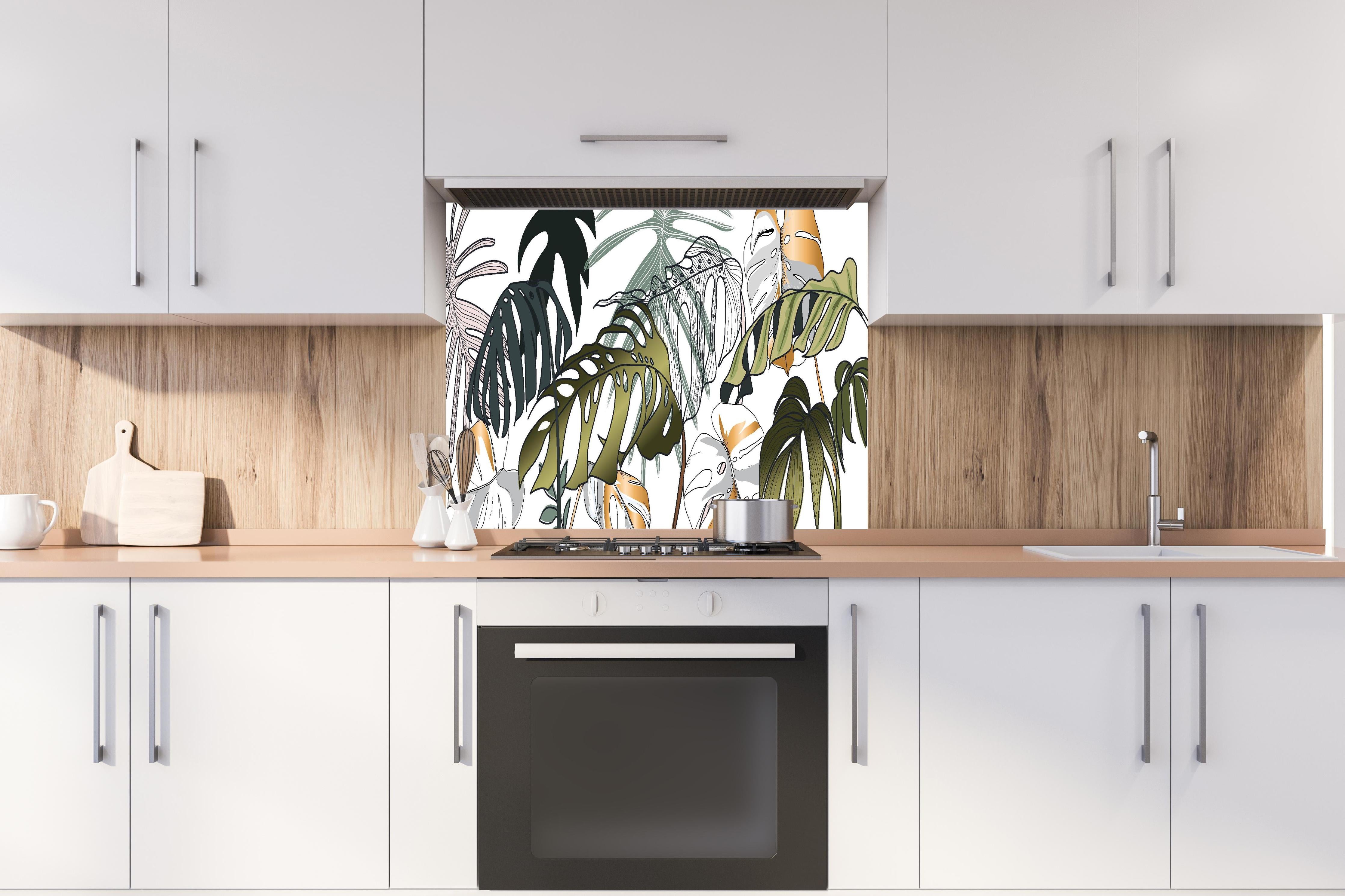 Spritzschutz - Grünes Tropenblättermuster für moderne Deko hinter einem Cerankochfeld zwischen Holz-Kochutensilien
