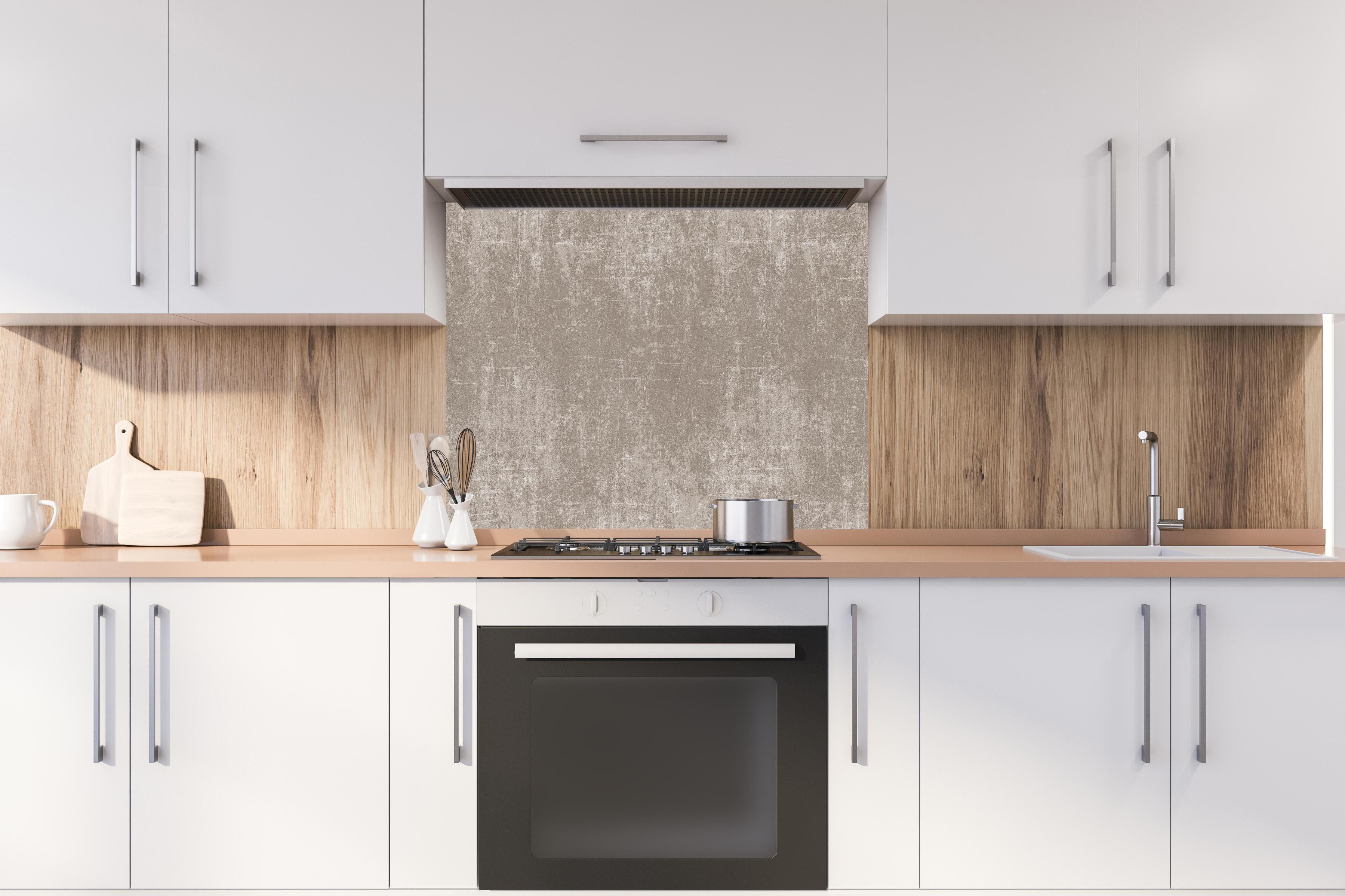 Spritzschutz - Heller Zementhintergrund hinter einem Cerankochfeld zwischen Holz-Kochutensilien
