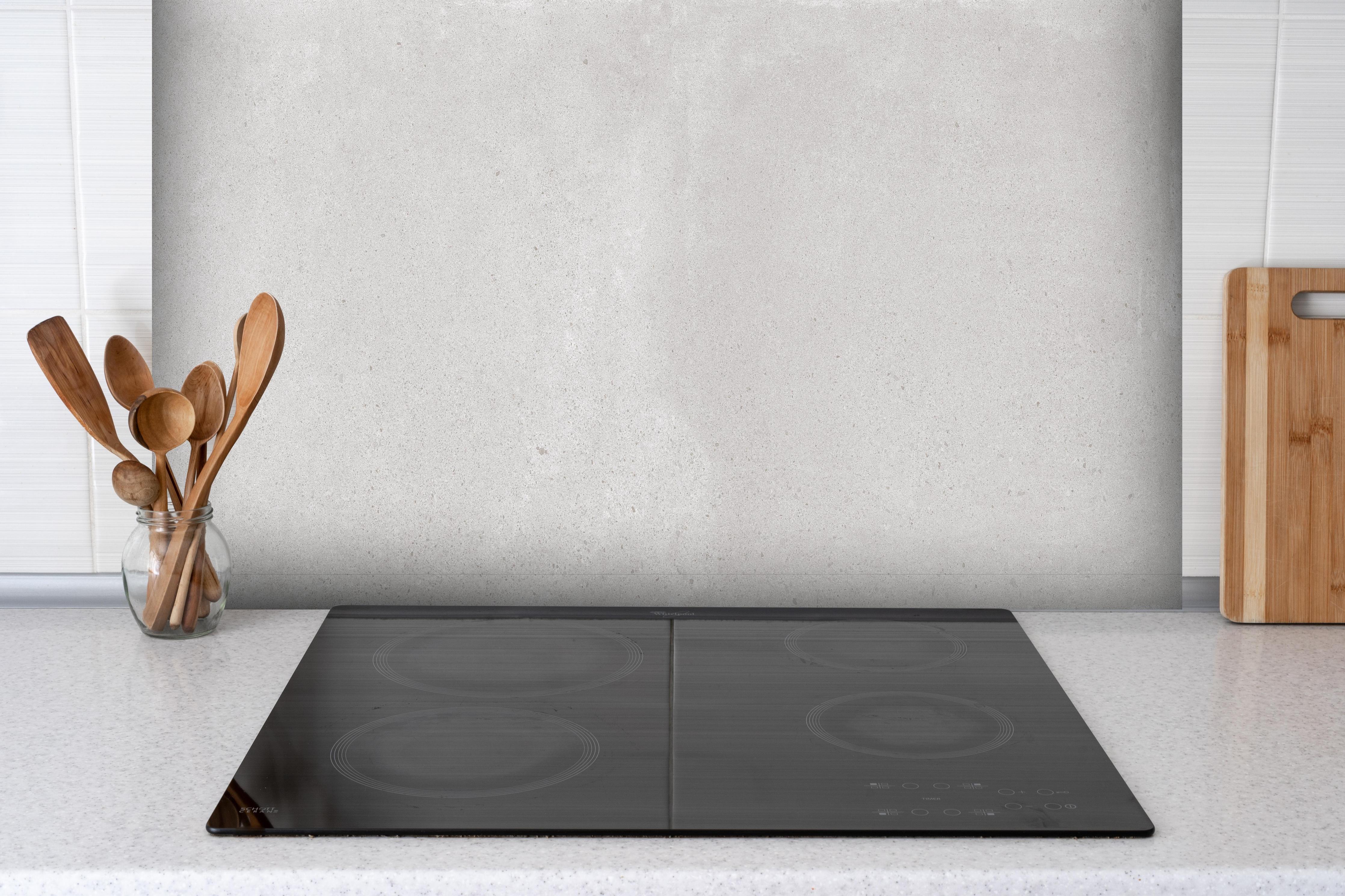 Spritzschutz - Hellgraues Mamor Design hinter einem Cerankochfeld zwischen Holz-Kochutensilien
