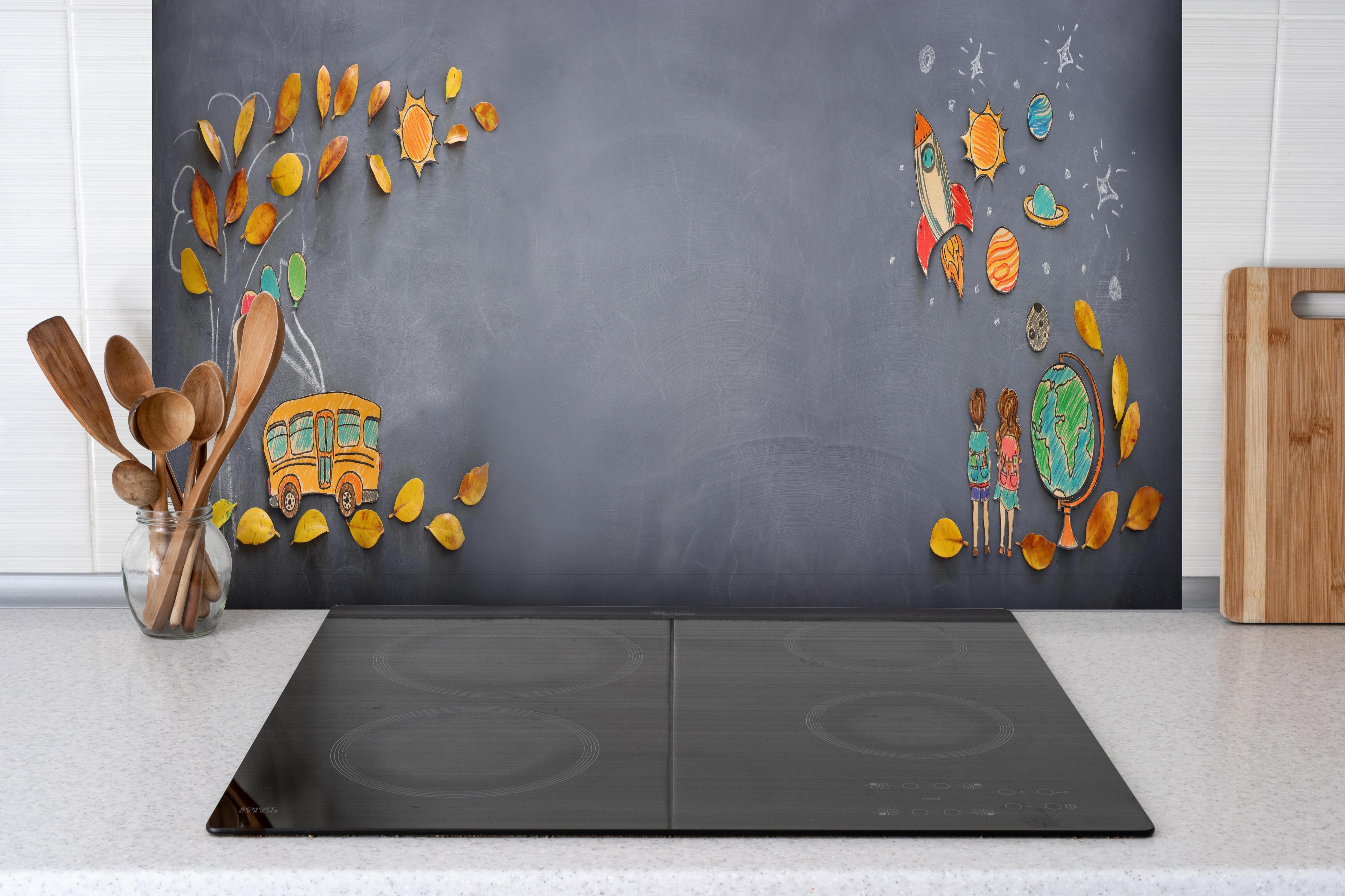 Spritzschutz - Herbstleaves und Schulbus auf Tafel hinter einem Cerankochfeld zwischen Holz-Kochutensilien
