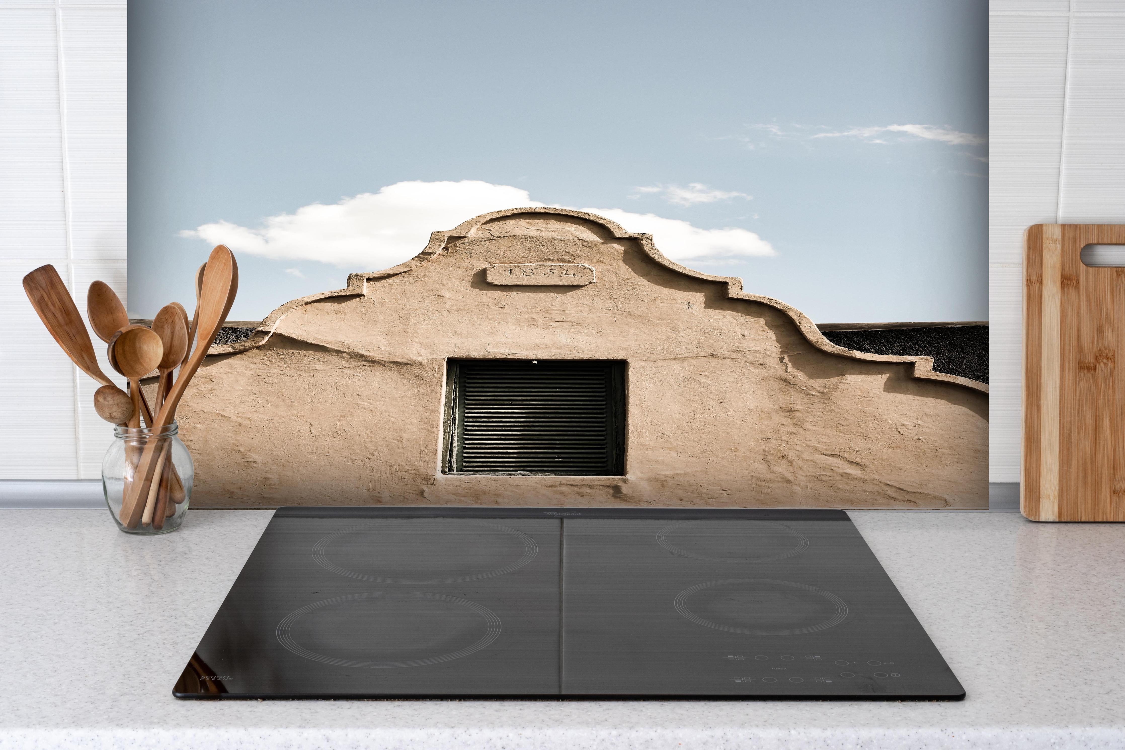 Spritzschutz - Historische Gebäudefassade unter Wolkenhimmel hinter einem Cerankochfeld zwischen Holz-Kochutensilien
