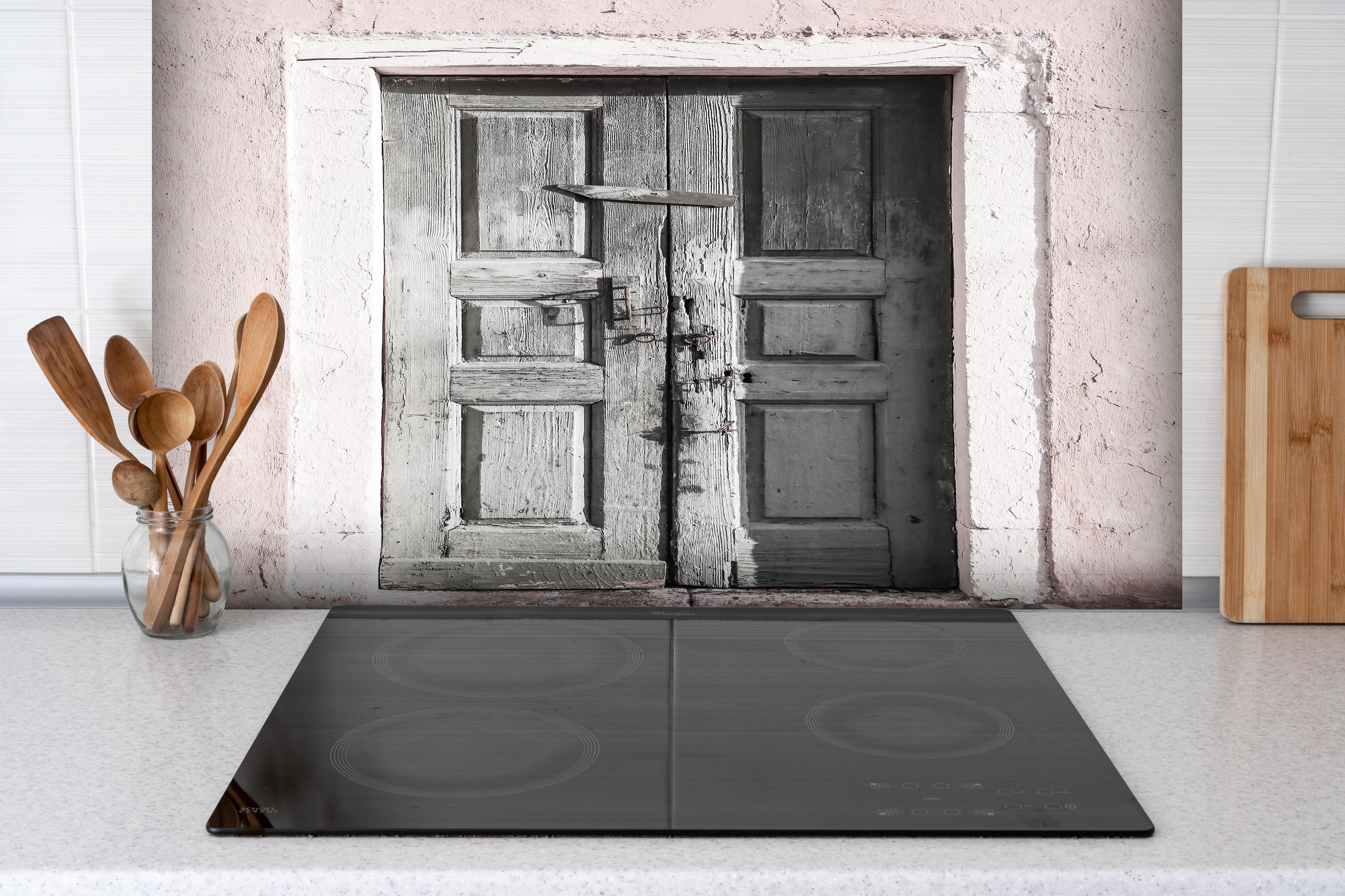 Spritzschutz - Historische Tür hinter einem Cerankochfeld zwischen Holz-Kochutensilien
