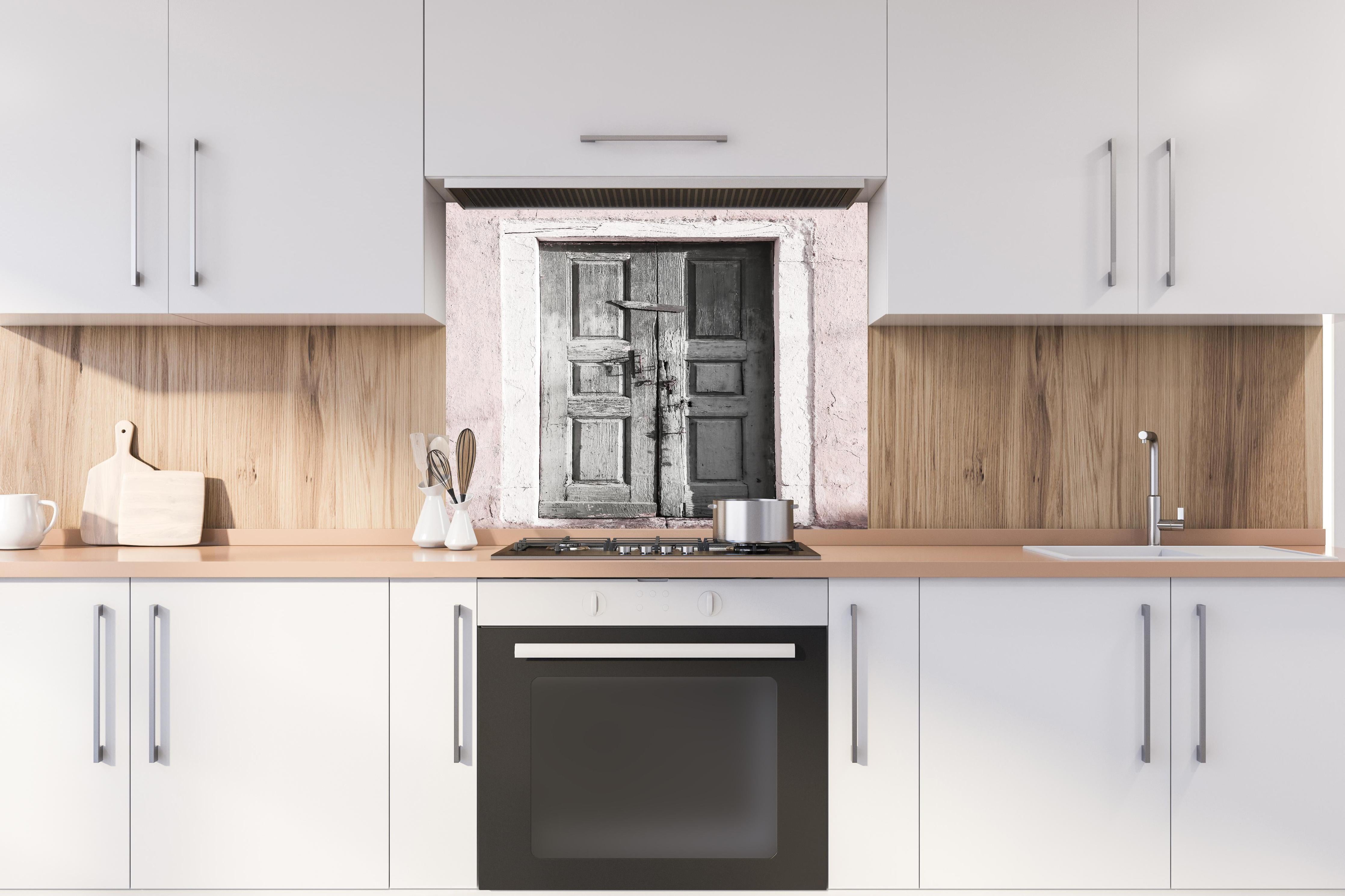 Spritzschutz - Historische Tür hinter einem Cerankochfeld zwischen Holz-Kochutensilien
