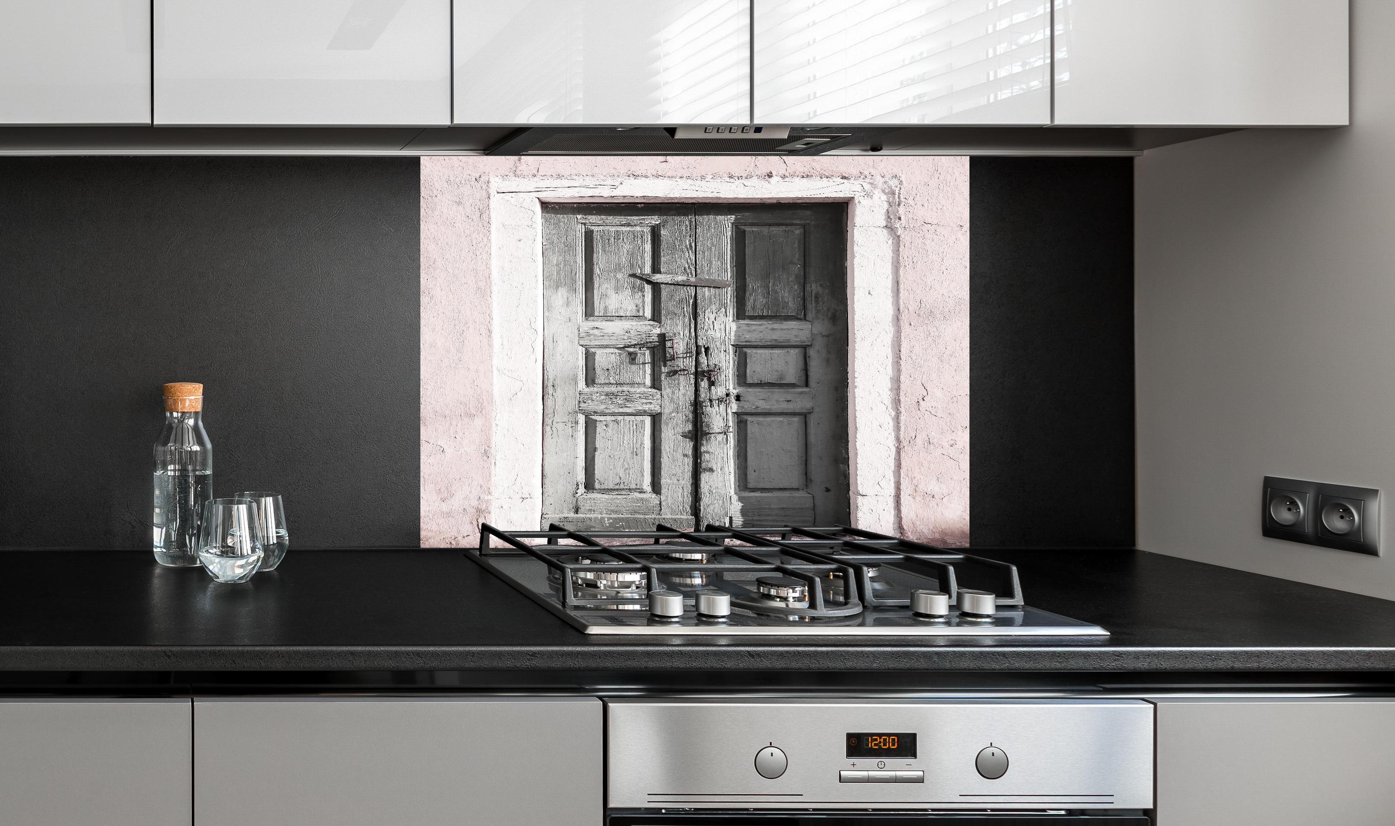 Spritzschutz - Historische Tür hinter einem Cerankochfeld zwischen Holz-Kochutensilien
