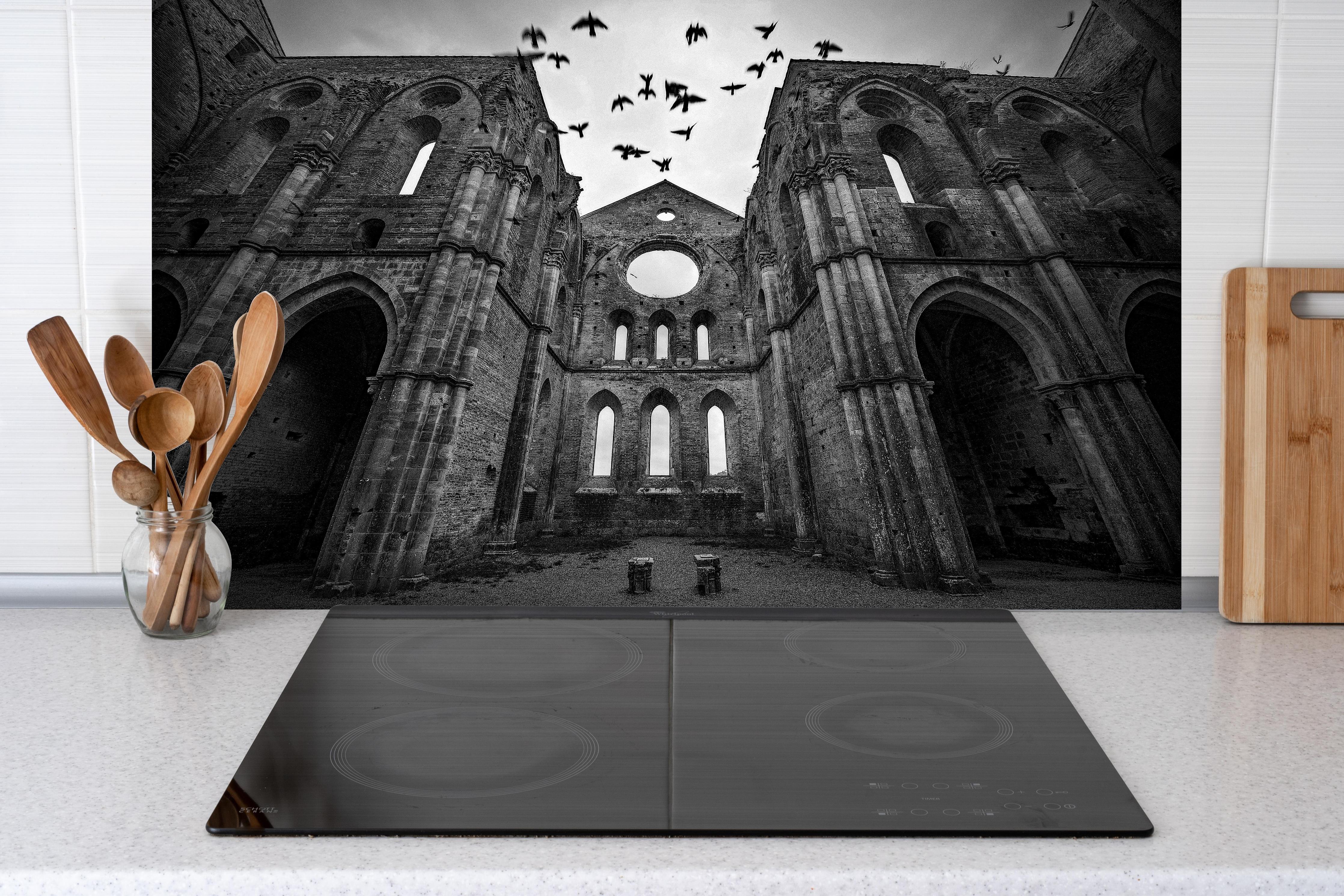 Spritzschutz - Historisches Kloster - San Galgano hinter einem Cerankochfeld zwischen Holz-Kochutensilien
