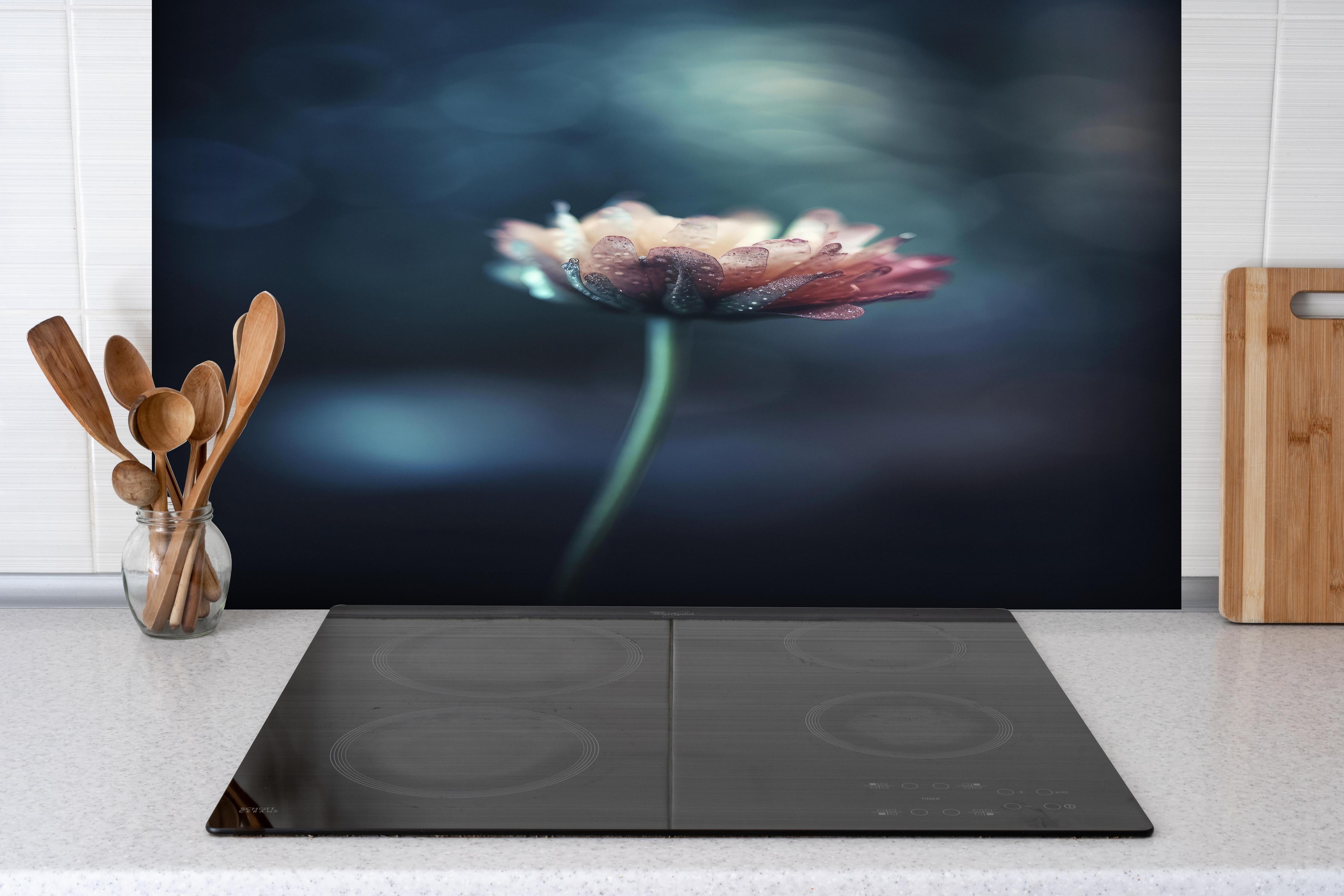 Spritzschutz - Hochauflösende Blume - verschwommen hinter einem Cerankochfeld zwischen Holz-Kochutensilien
