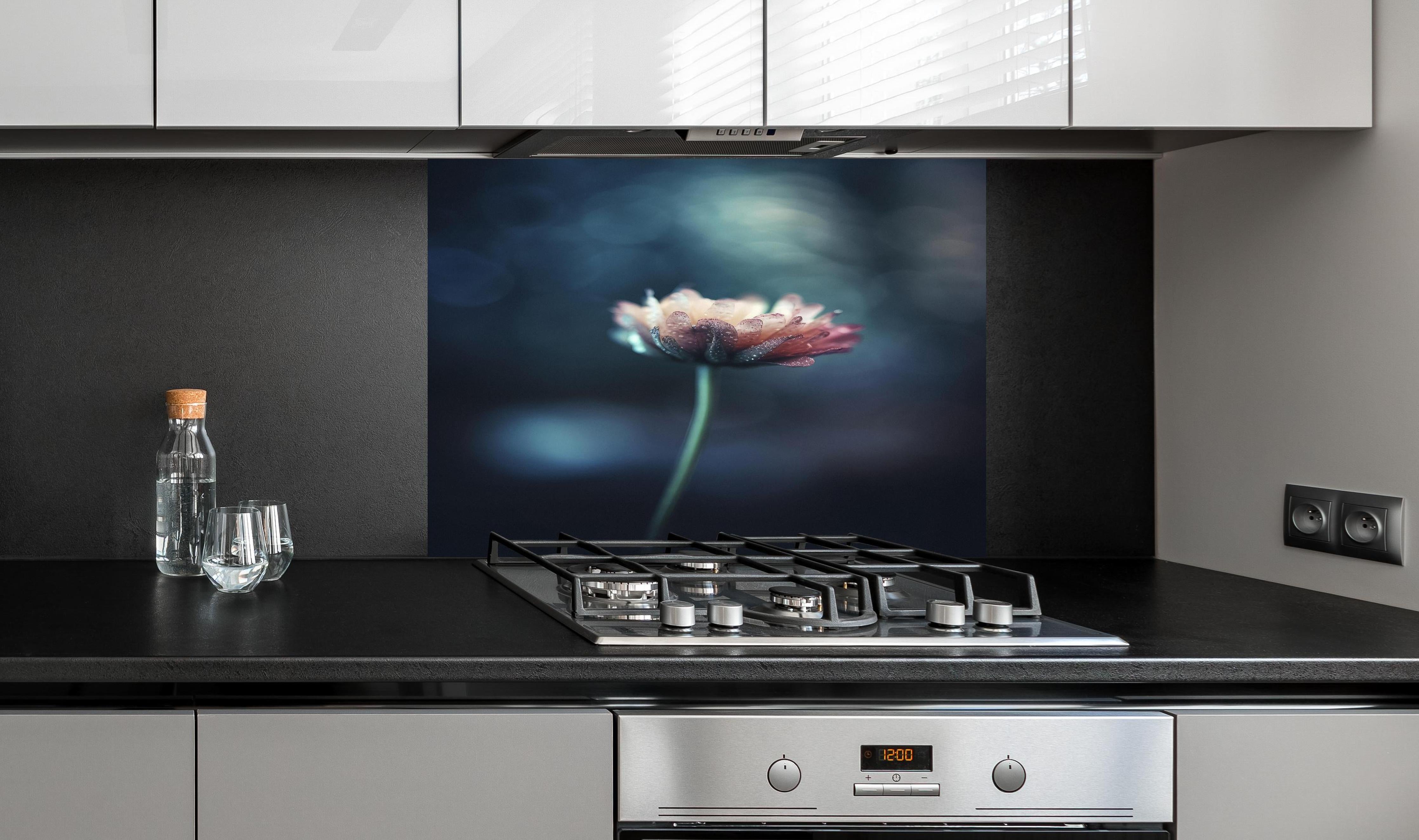 Spritzschutz - Hochauflösende Blume - verschwommen hinter einem Cerankochfeld zwischen Holz-Kochutensilien
