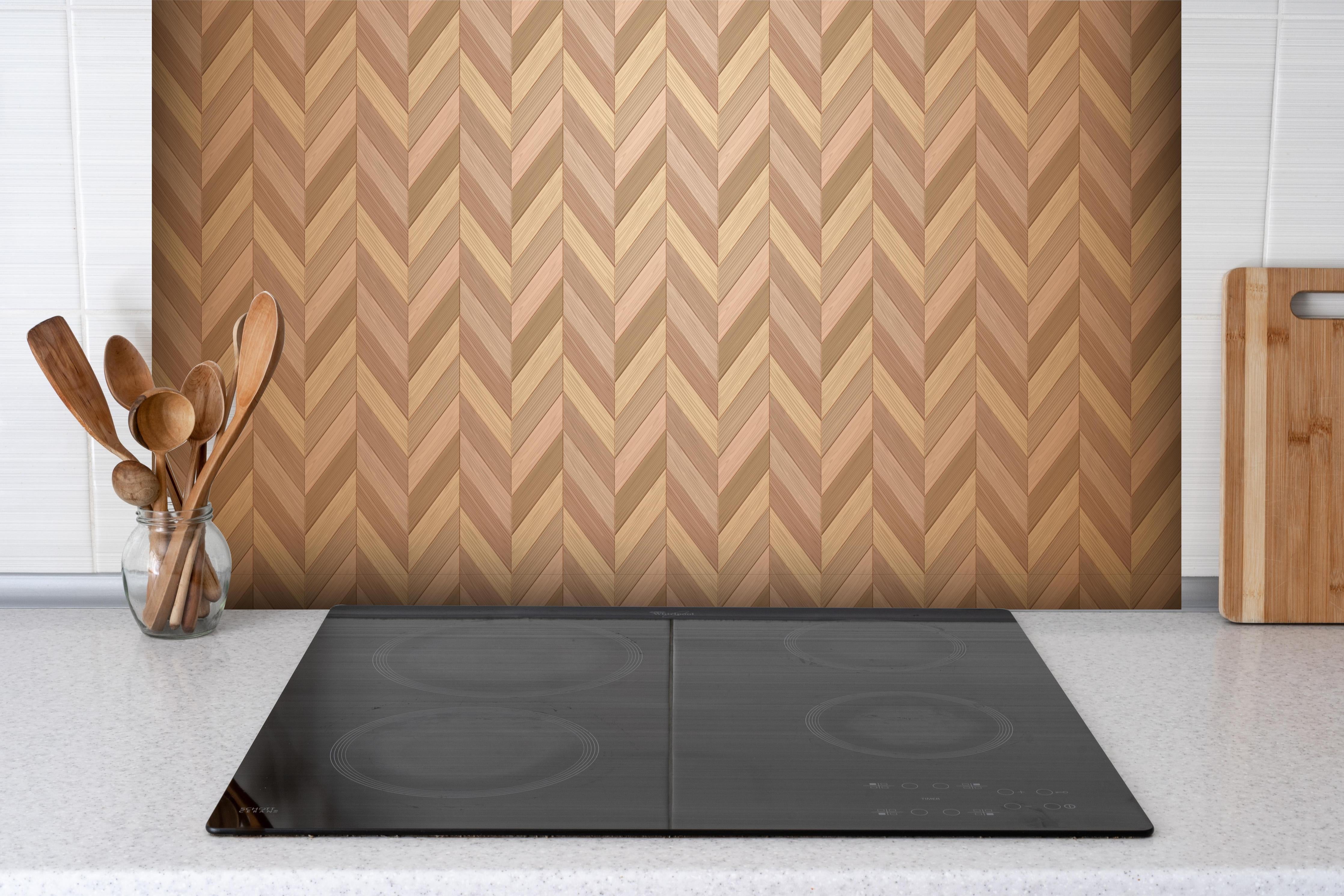 Spritzschutz - Hochwertiger Fischgrät Parkettboden in Braun hinter einem Cerankochfeld zwischen Holz-Kochutensilien
