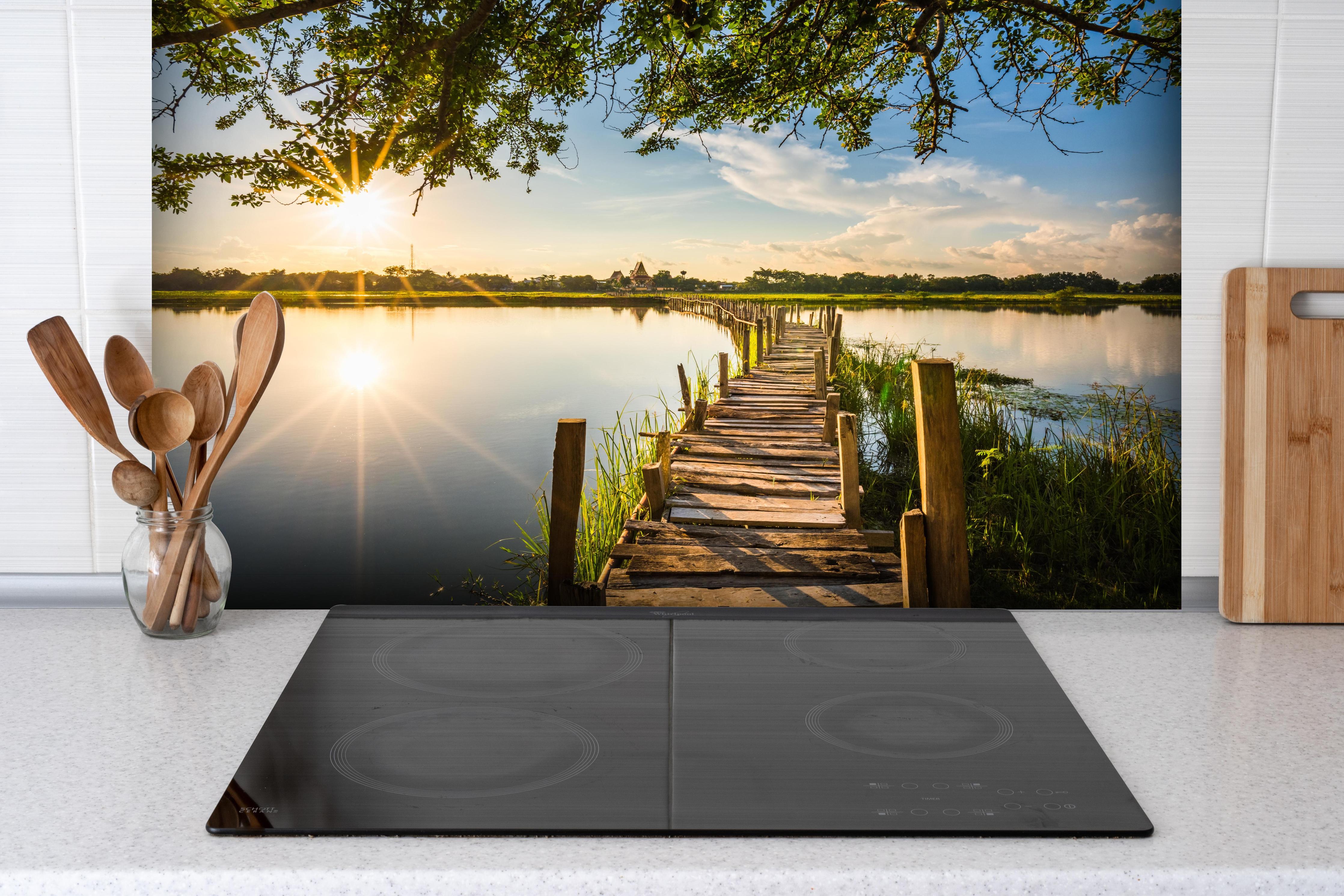 Spritzschutz - Holzbrücke am See - Thailand hinter einem Cerankochfeld zwischen Holz-Kochutensilien
