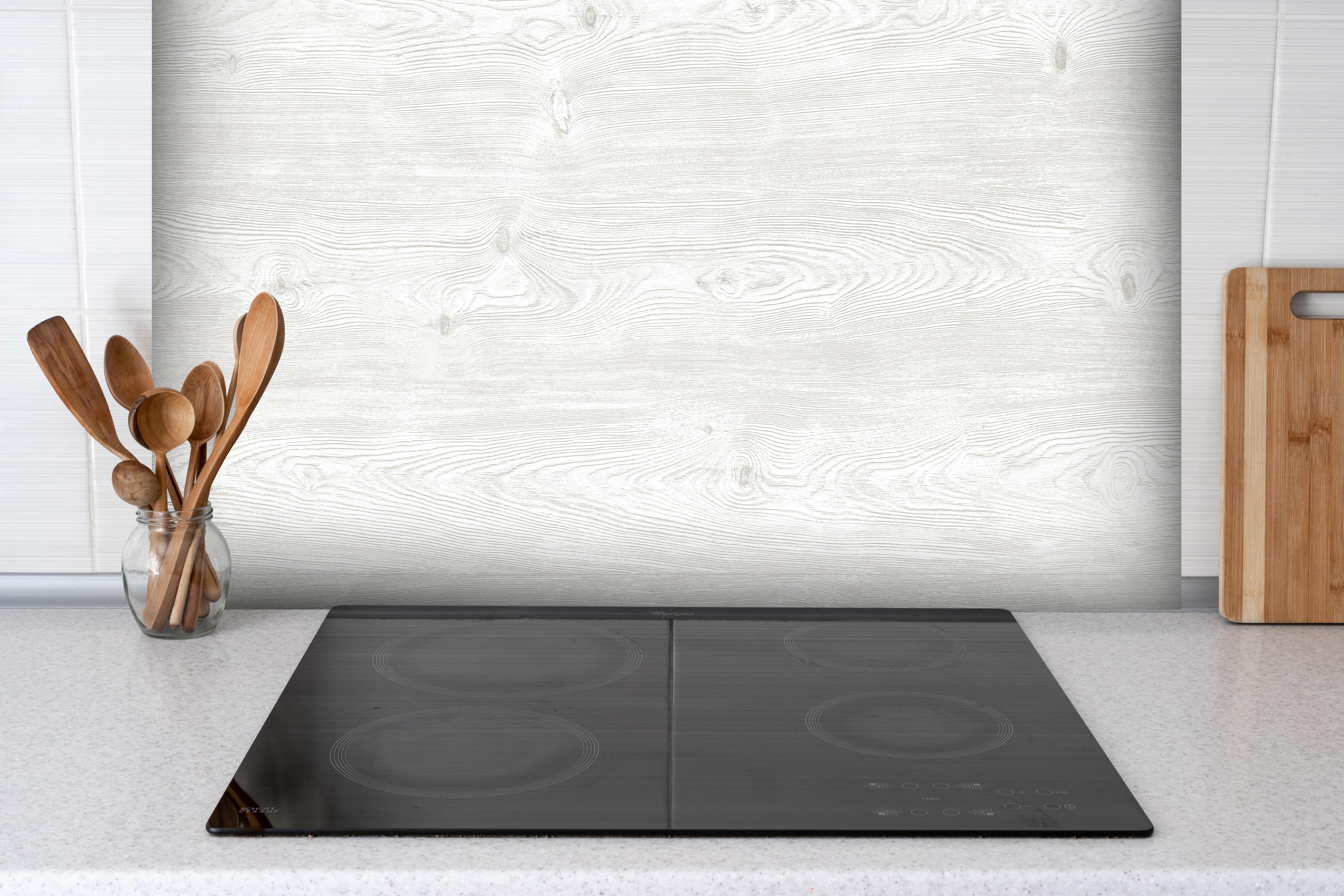 Spritzschutz - Holzoptik - hell hinter einem Cerankochfeld zwischen Holz-Kochutensilien
