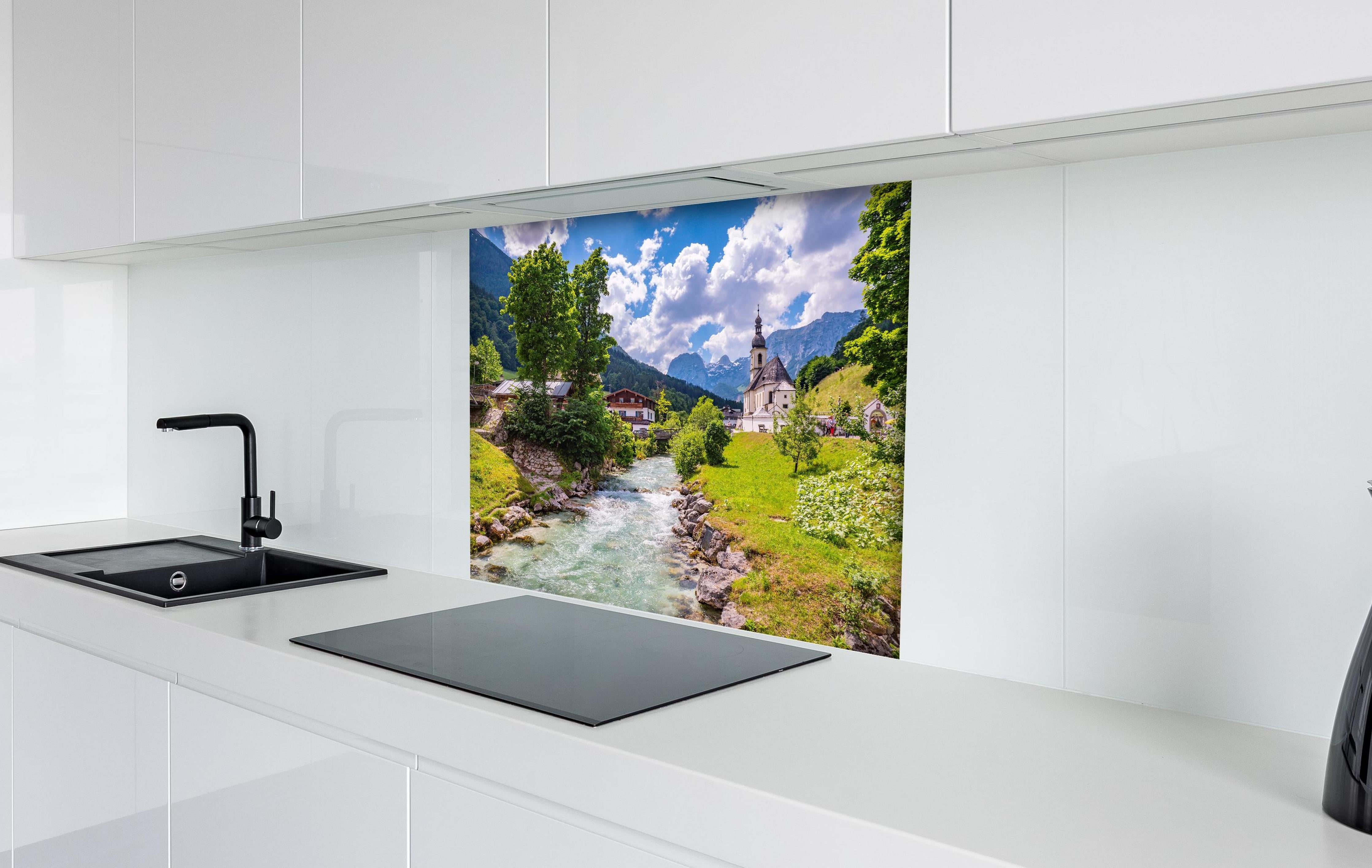 Spritzschutz - Idyllische Ramsau Kirche mit Bergblick hinter einem Cerankochfeld zwischen Holz-Kochutensilien
