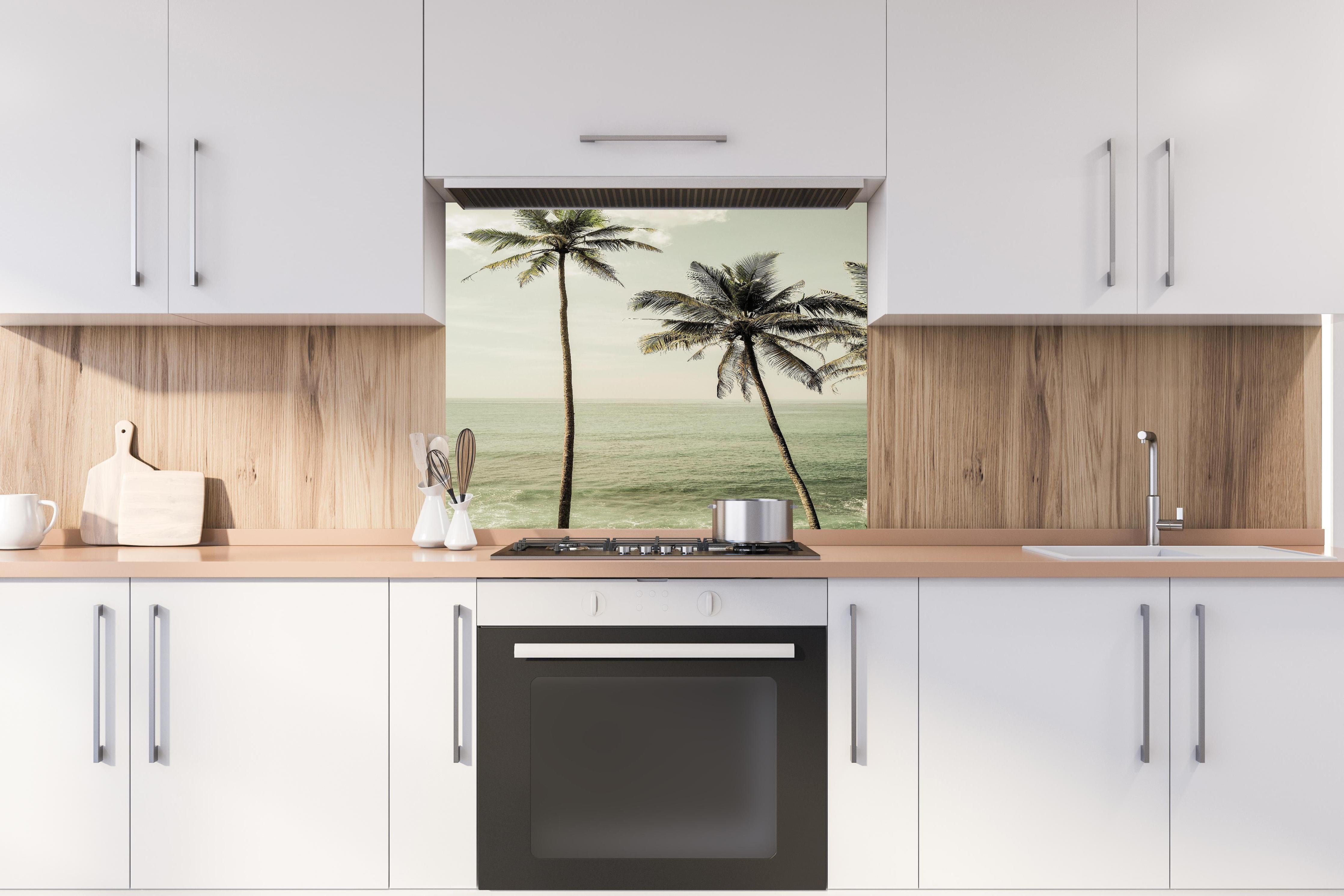 Spritzschutz - Idyllische Strandpalmen über ruhigem Meer hinter einem Cerankochfeld zwischen Holz-Kochutensilien
