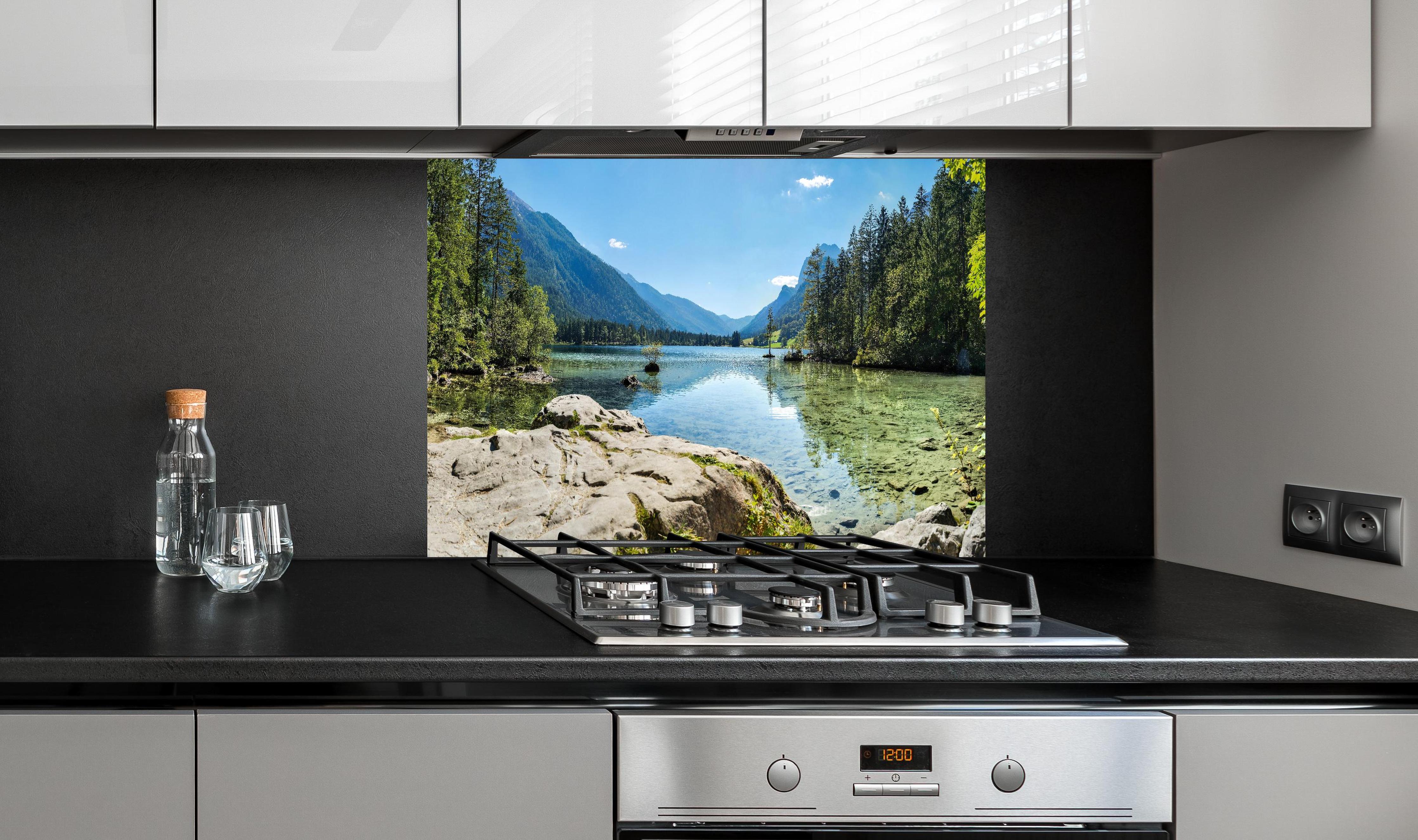 Spritzschutz - Idyllischer Königssee hinter einem Cerankochfeld zwischen Holz-Kochutensilien
