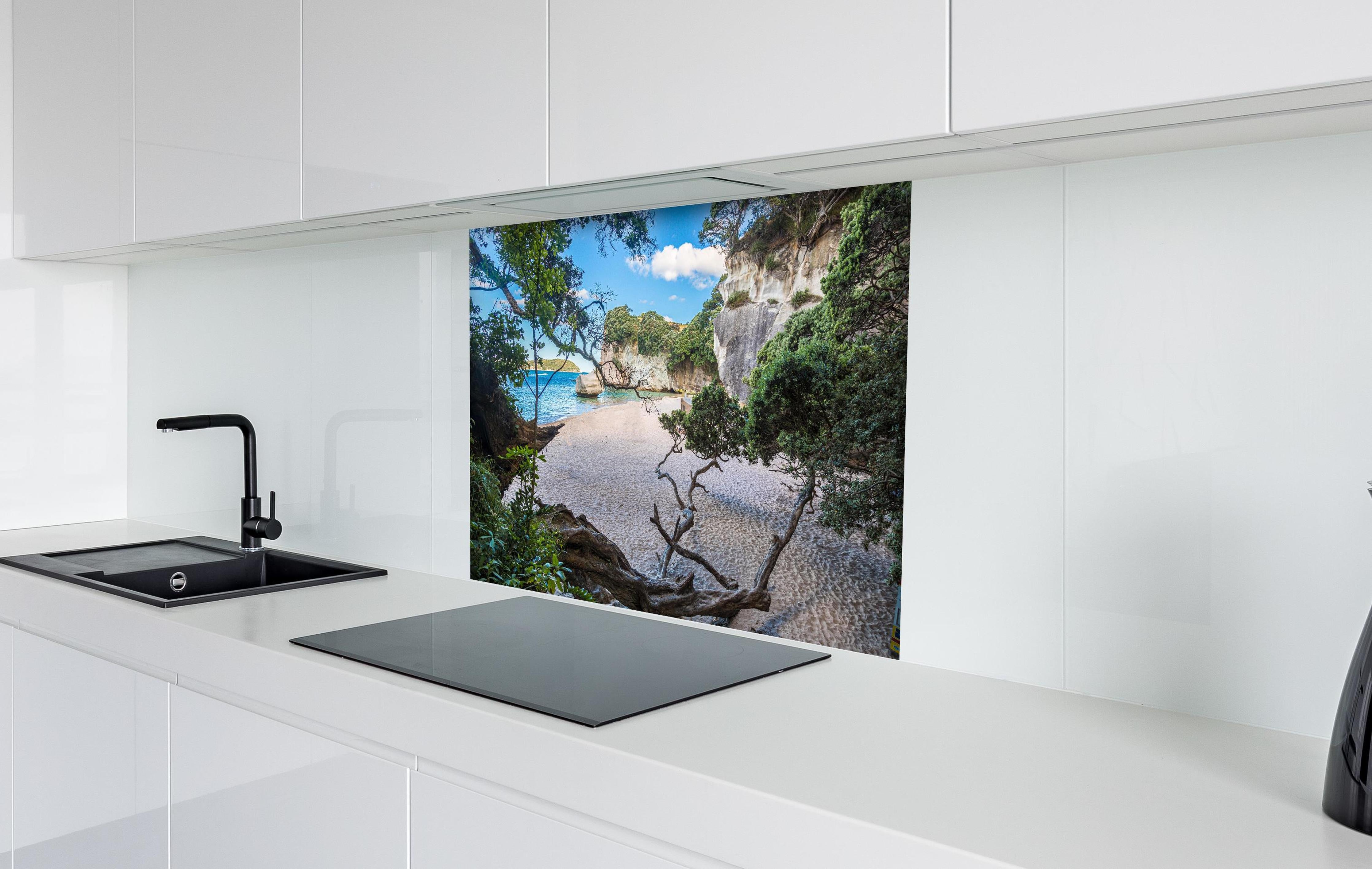 Spritzschutz - Idyllischer Sommerstrand Cathedral Cove hinter einem Cerankochfeld zwischen Holz-Kochutensilien
