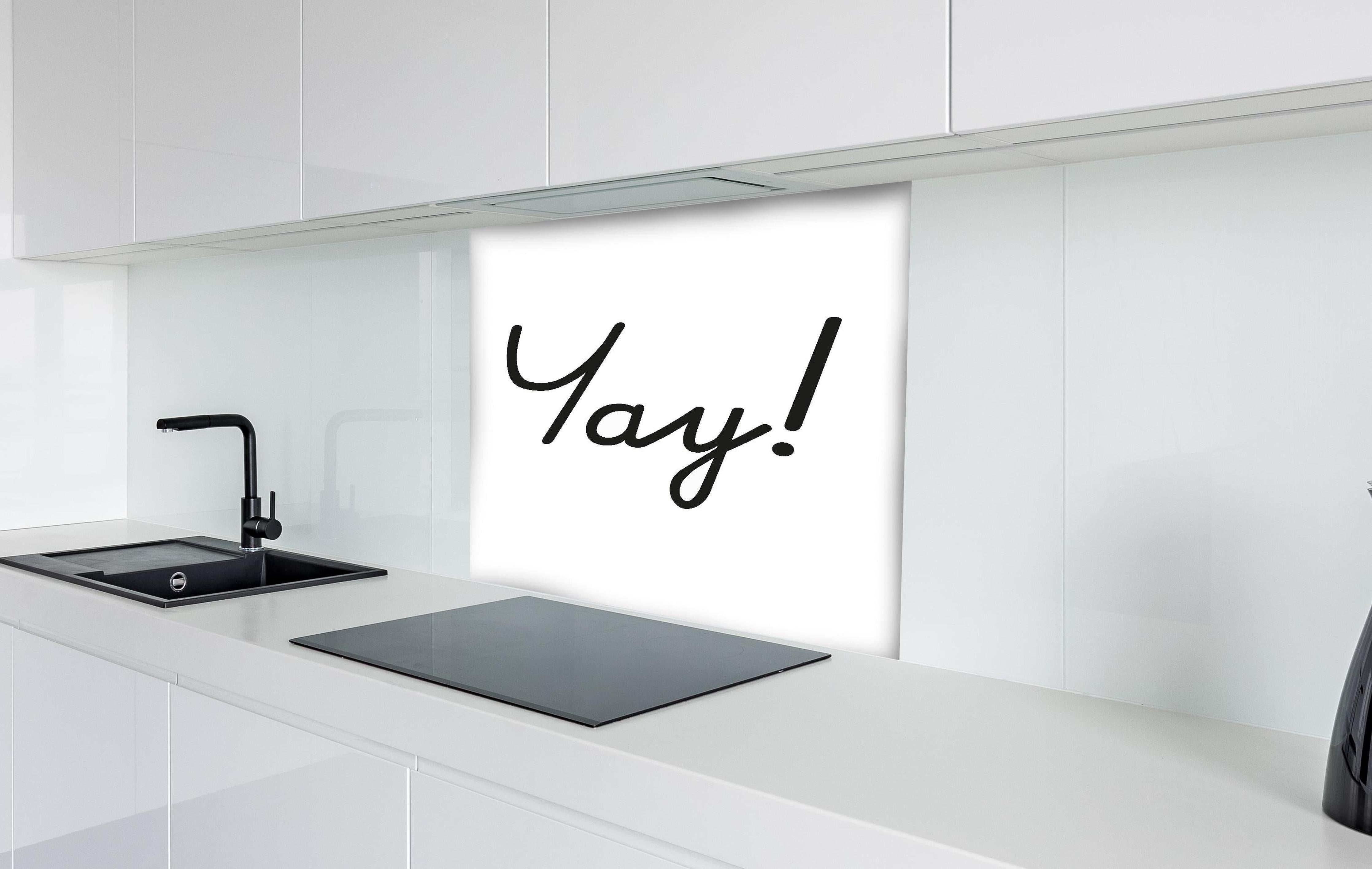 Spritzschutz - Inspirierender 'Yay!' Schriftzug in Schwarz auf Weiß hinter einem Cerankochfeld zwischen Holz-Kochutensilien
